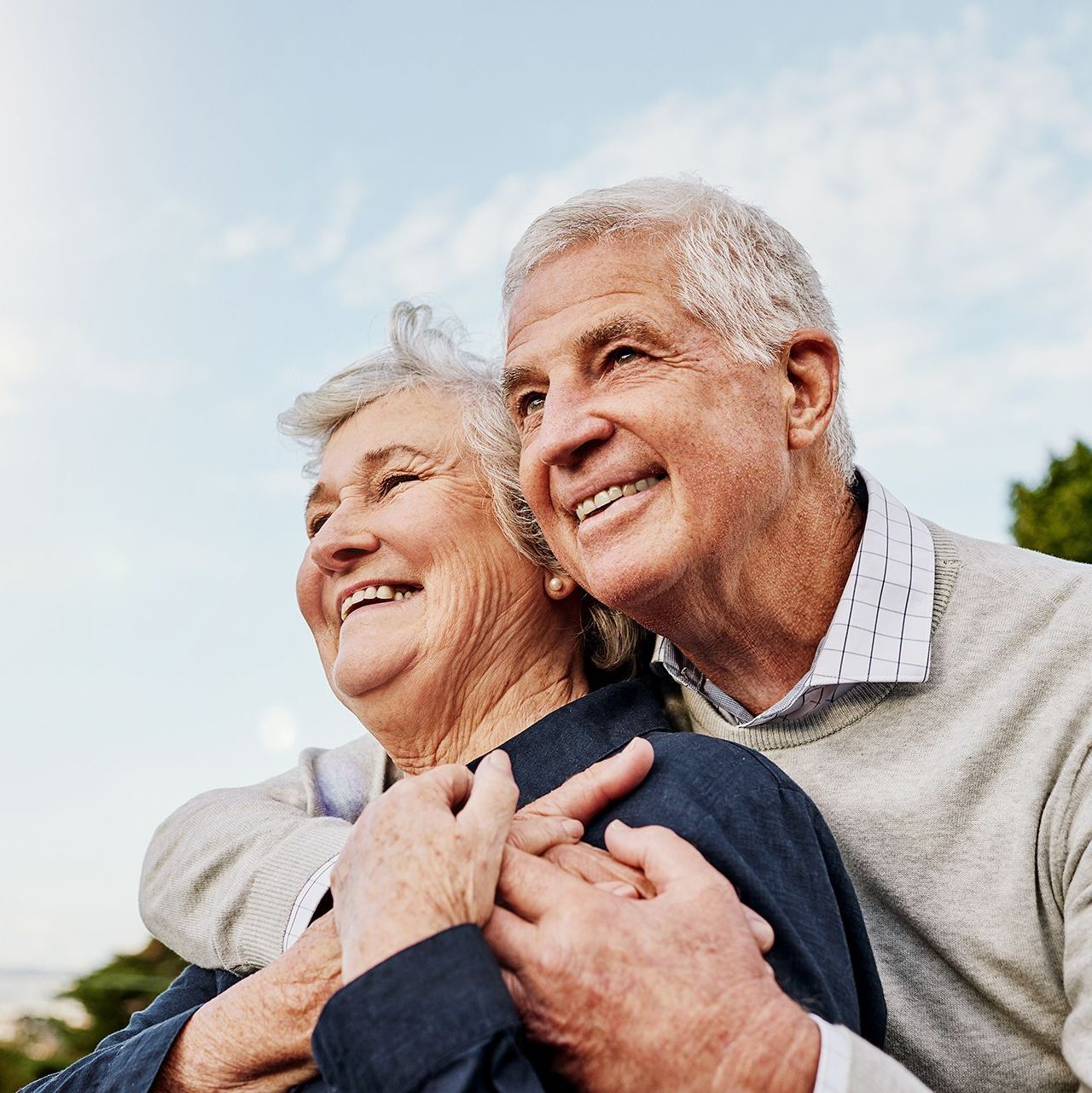 A man and a woman are hugging each other and smiling.