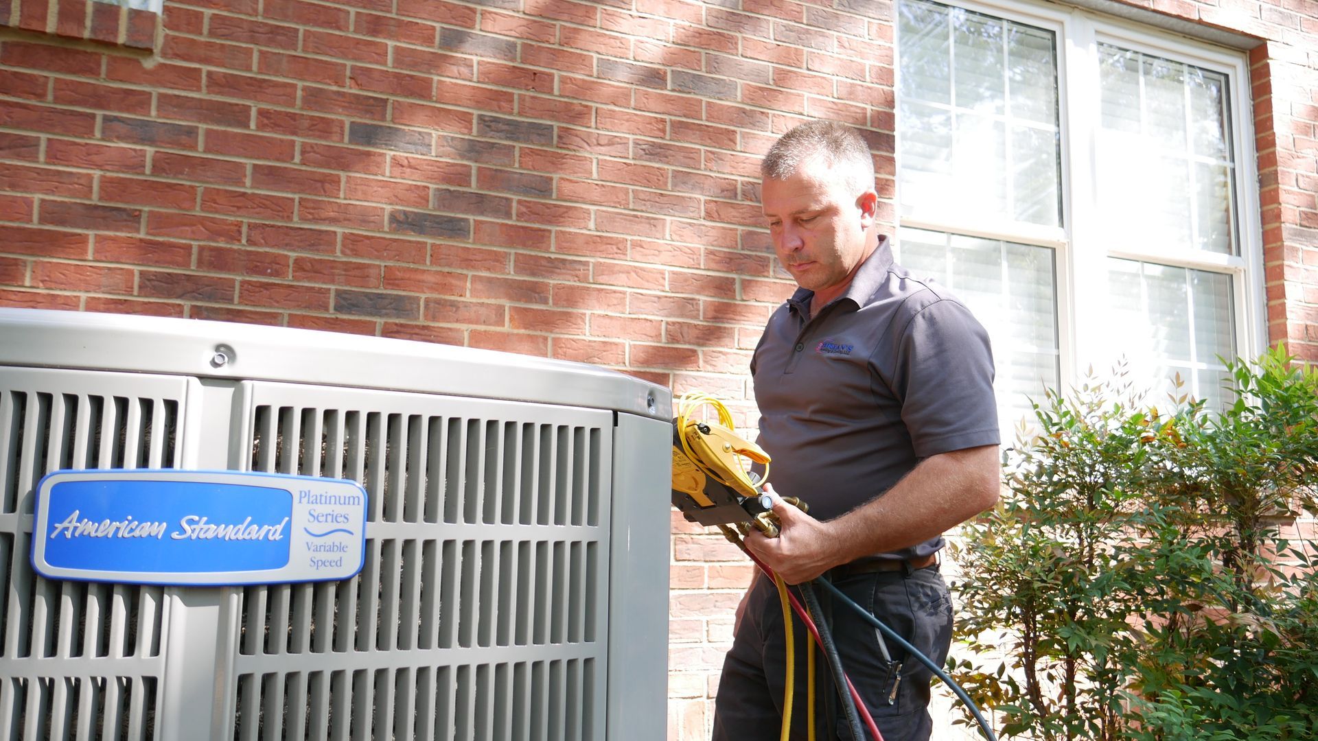 a man is working on an air conditioner outside of a brick building .