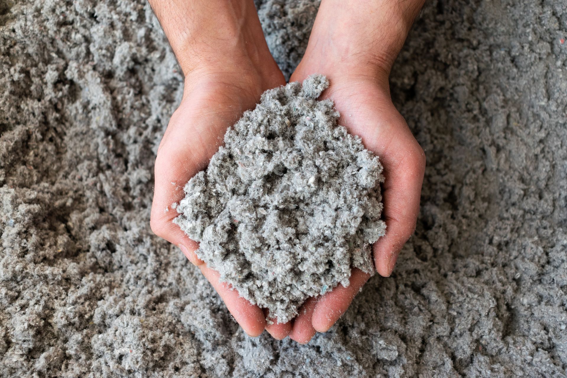 A person is holding a pile of concrete in their hands.