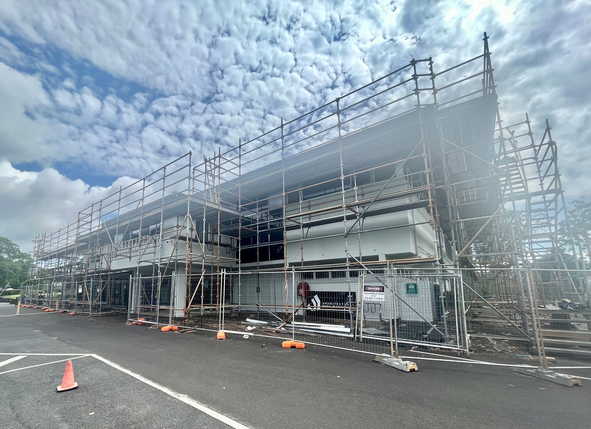 Full-building scaffolding surrounding a two-storey commercial structure, enclosed by temporary fencing for construction or renovation work. — Lennox Head Scaffolding in Ballina, NSW