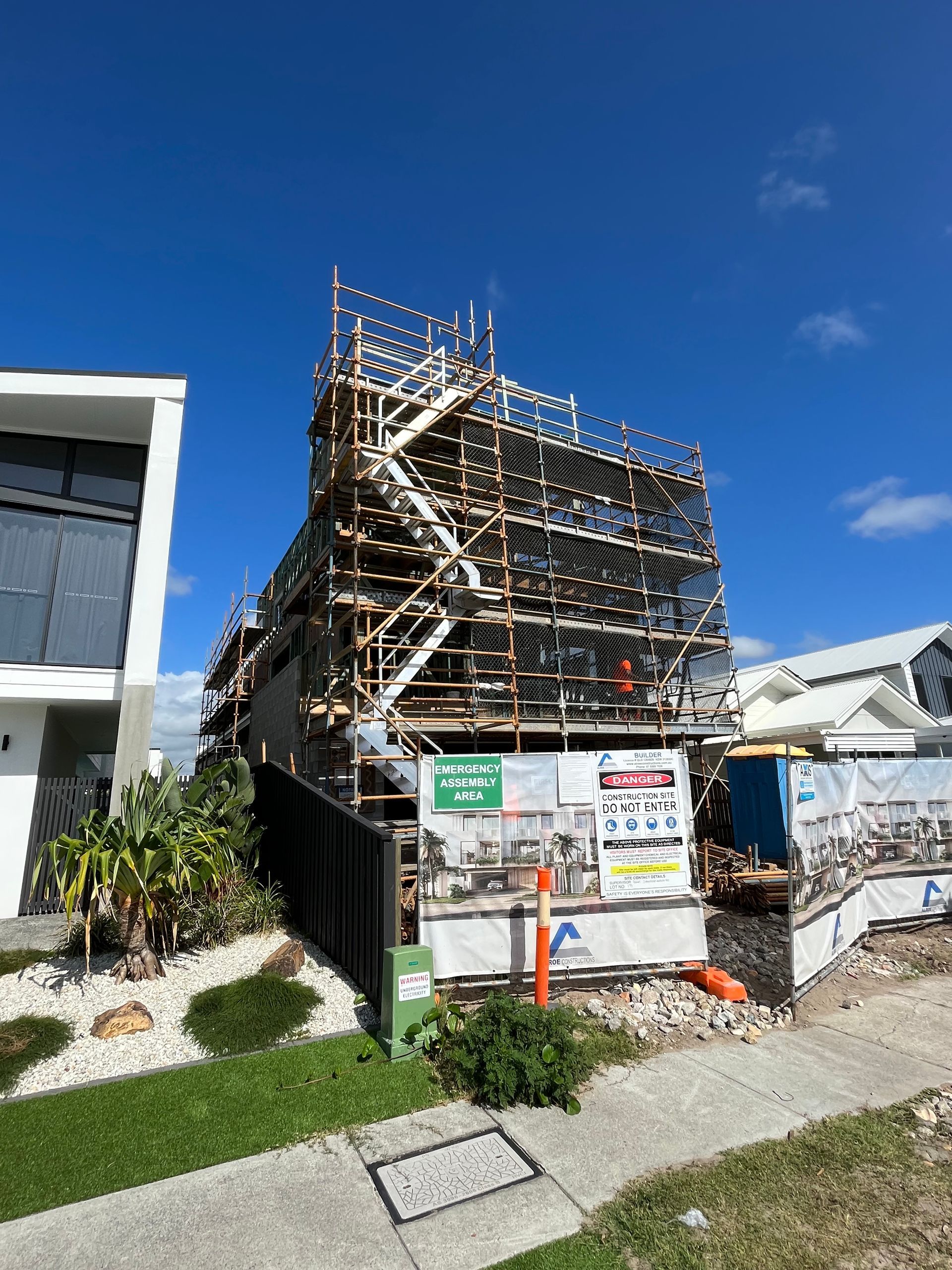 Tall, narrow residential building under construction, fully enclosed with scaffolding and safety mesh. — Lennox Head Scaffolding in Gold Coast, QLD