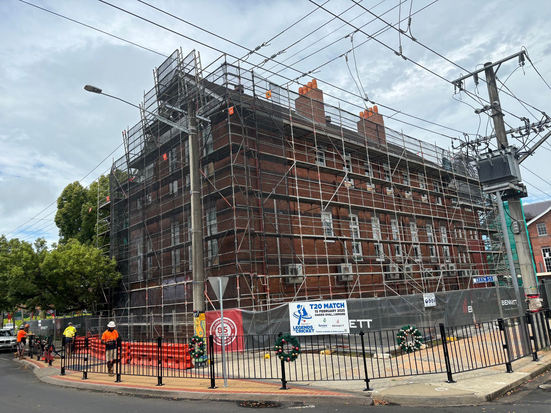 Large historic brick building wrapped in scaffolding, with workers and street fencing in the foreground. — Lennox Head Scaffolding in Lismore, NSW