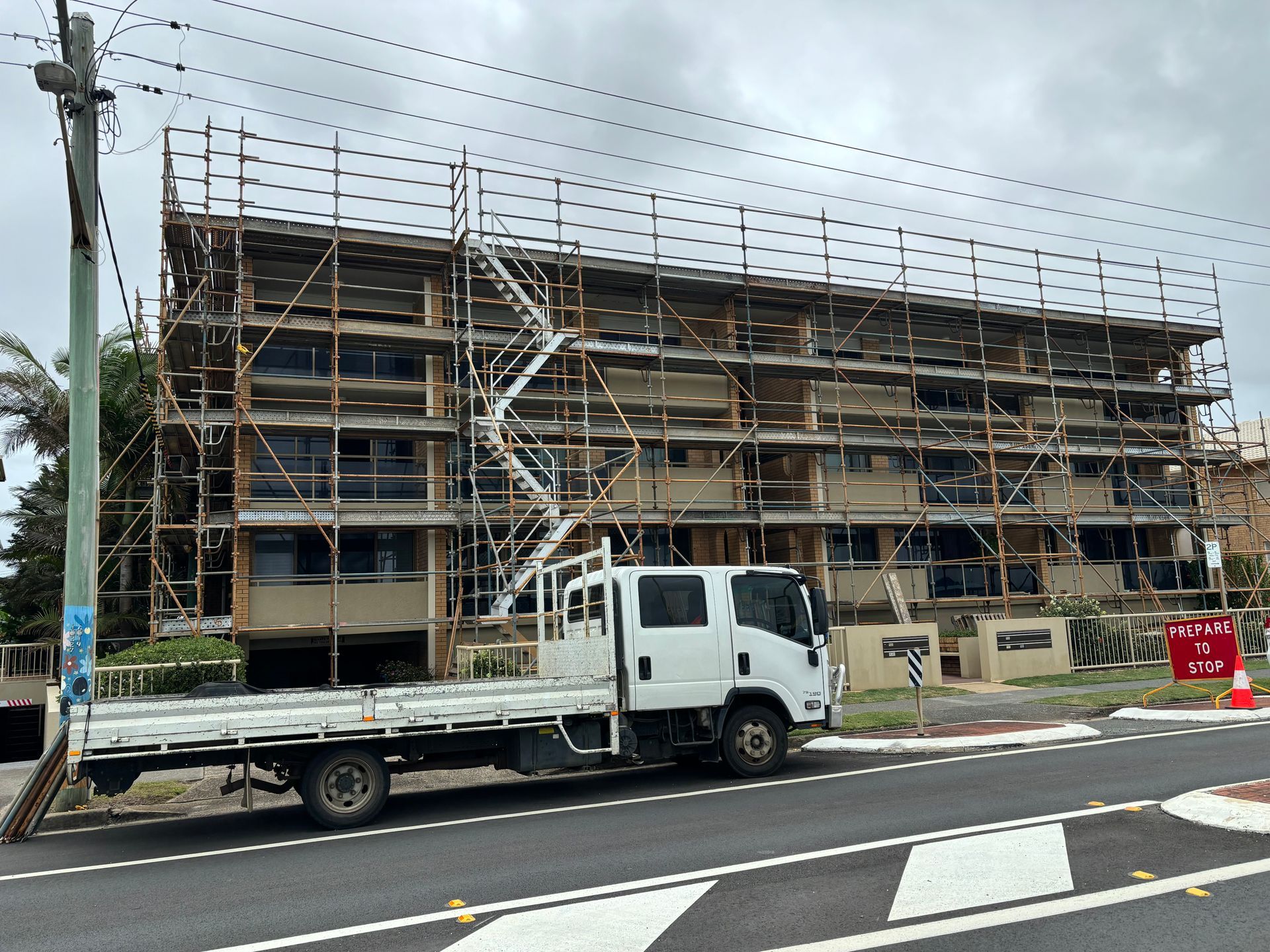 Mid-rise apartment building with scaffolding covering the facade, truck parked in front.
— Lennox Head Scaffolding in Tweed Heads, NSW