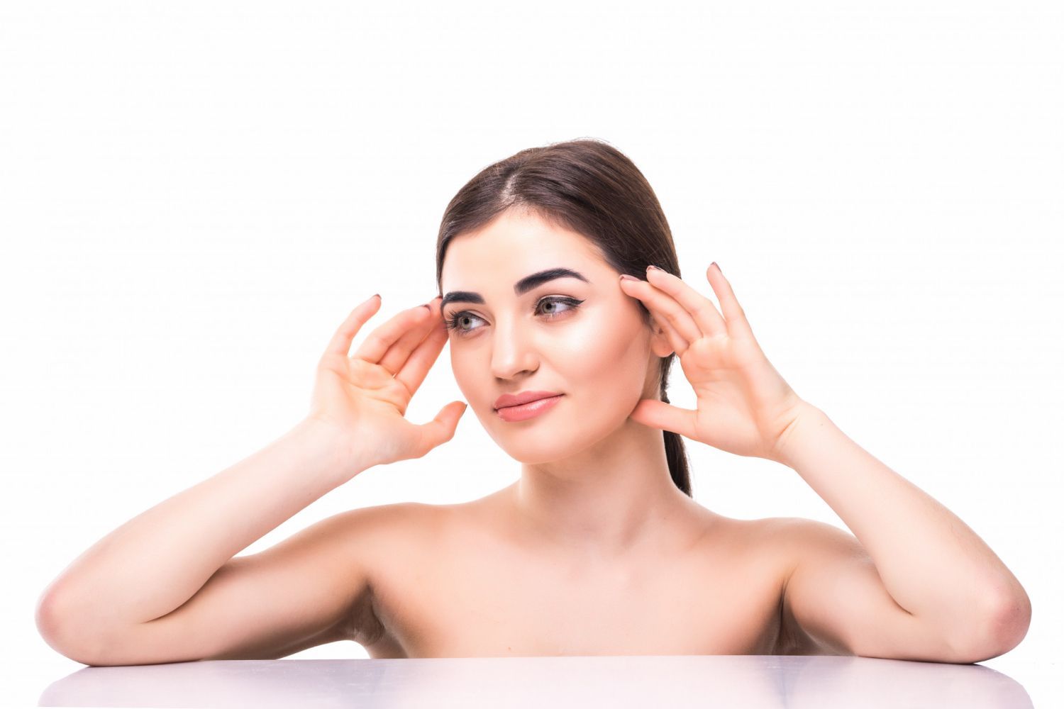 A woman is sitting at a table with her hands on her ears.