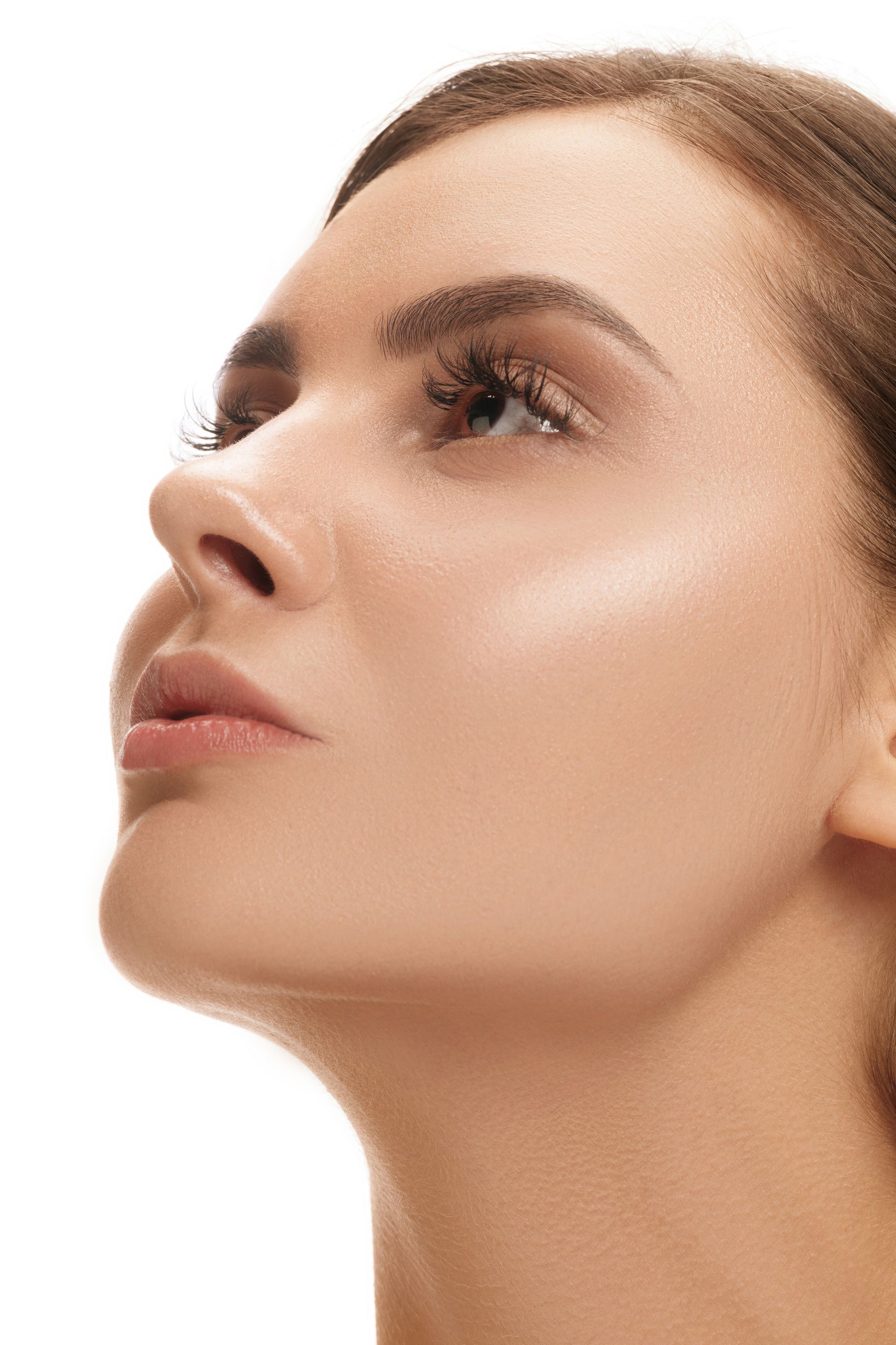 A close up of a woman 's face on a white background looking up.