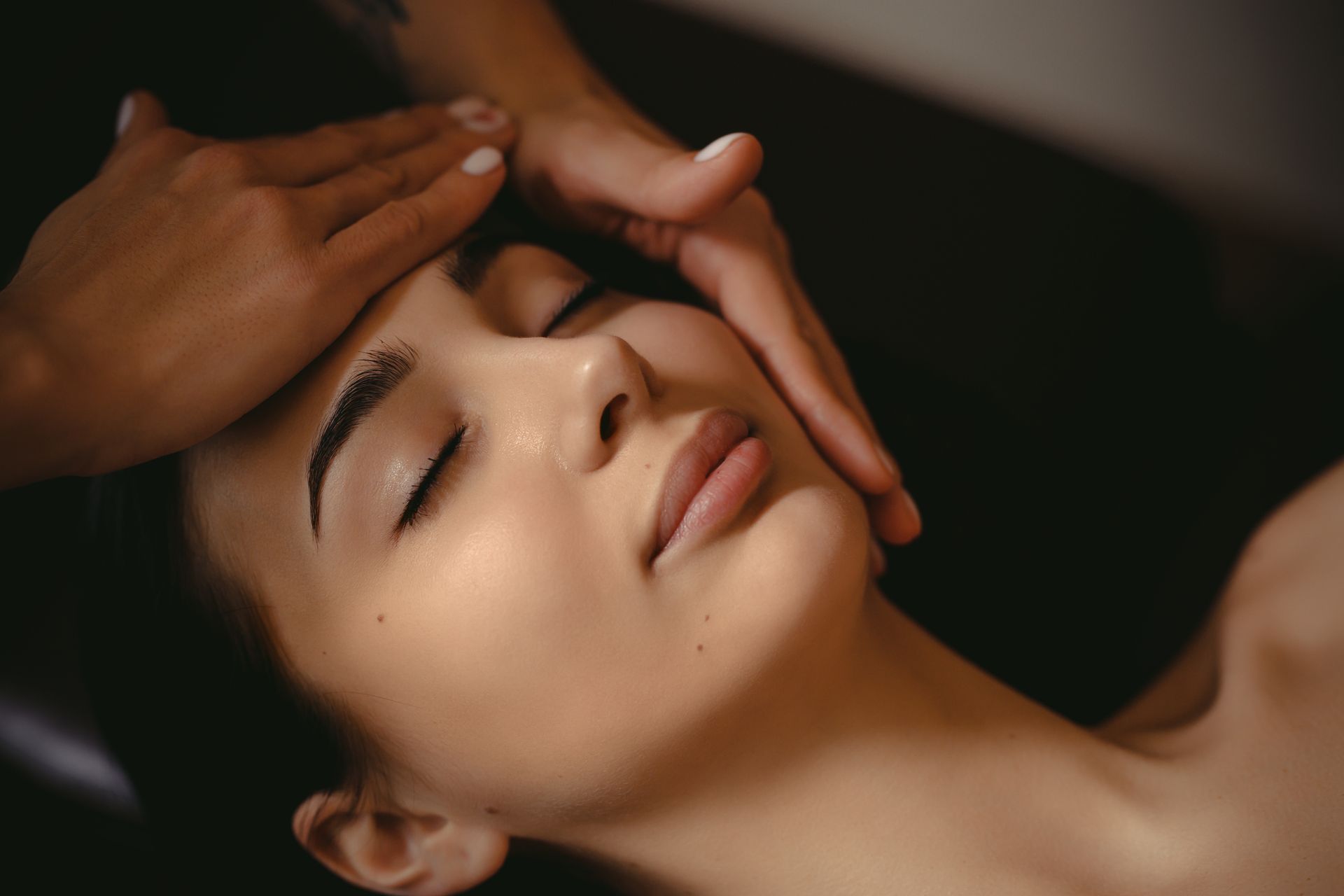 A woman is getting a facial massage at a spa.