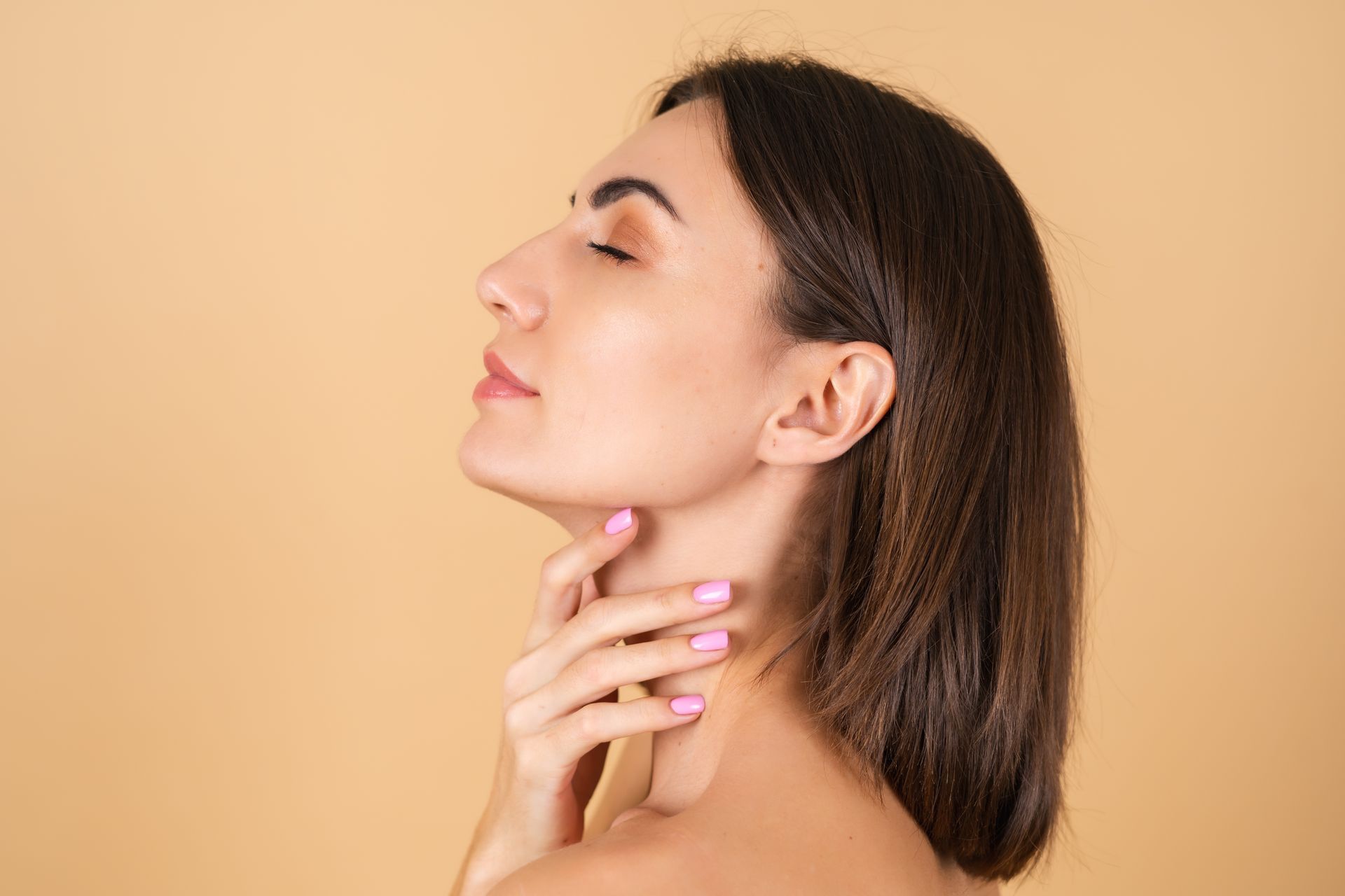 a woman with pink nail polish touching her neck