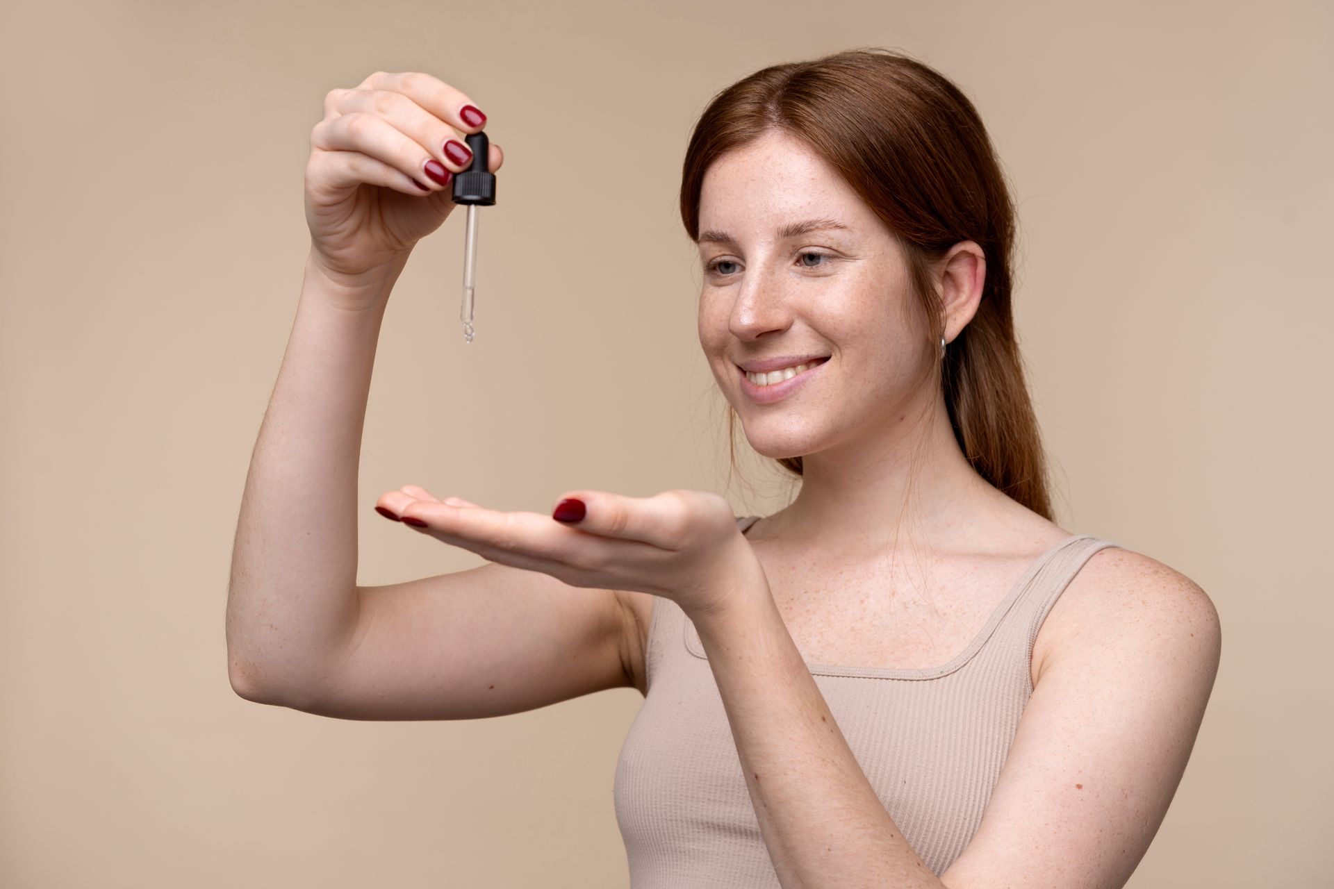 a woman with red nails is holding a dropper in her hand