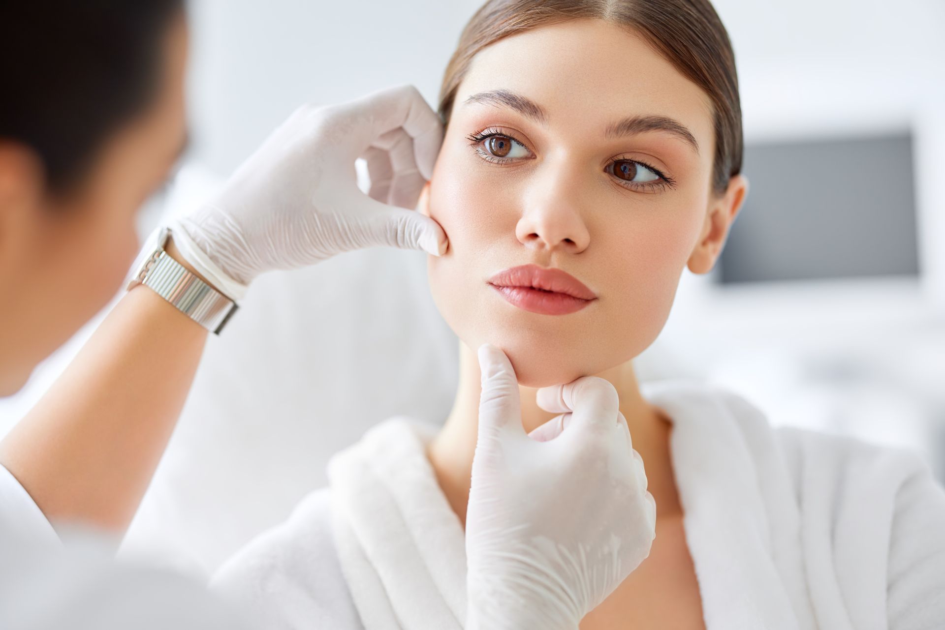 A woman is getting her face examined by a doctor.