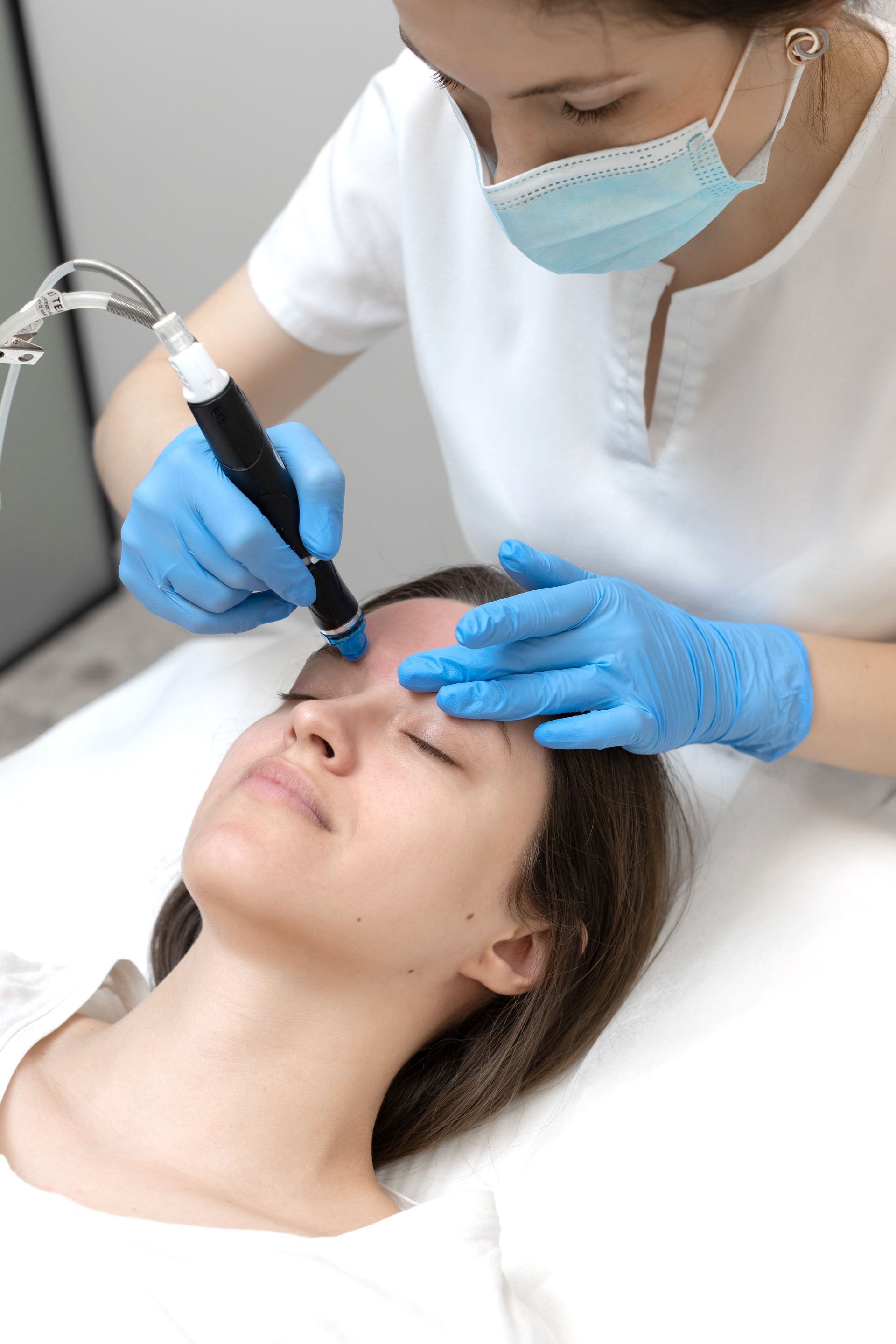 a woman wearing a mask and blue gloves is getting a treatment on her face