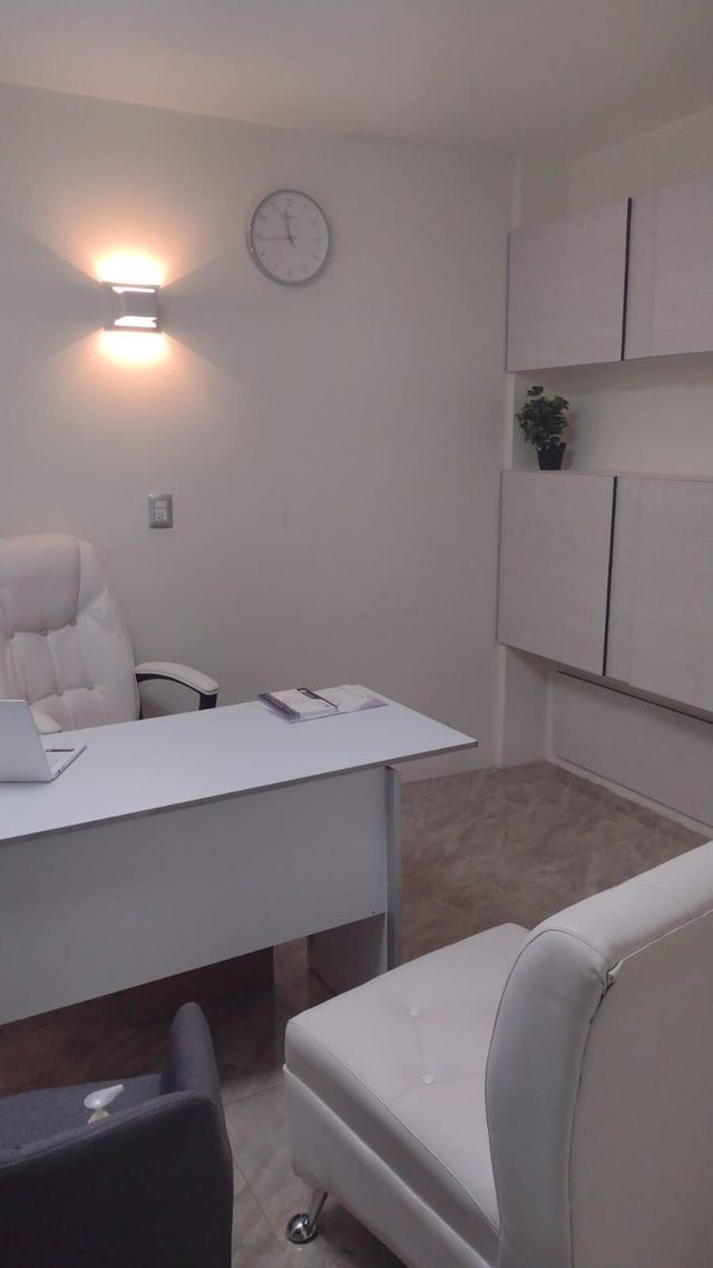 Una habitación con un escritorio, una silla y un reloj en la pared