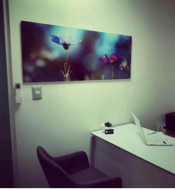 Una imagen de flores cuelga sobre un escritorio con una computadora portátil encima