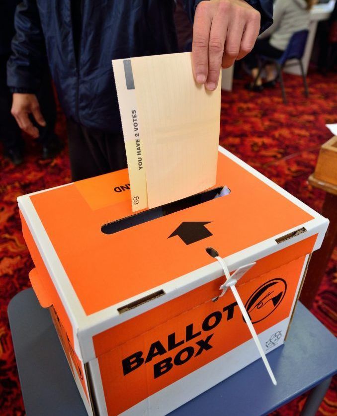 DormFIN Insurance Broker vote A person is putting a ballot in a ballot box