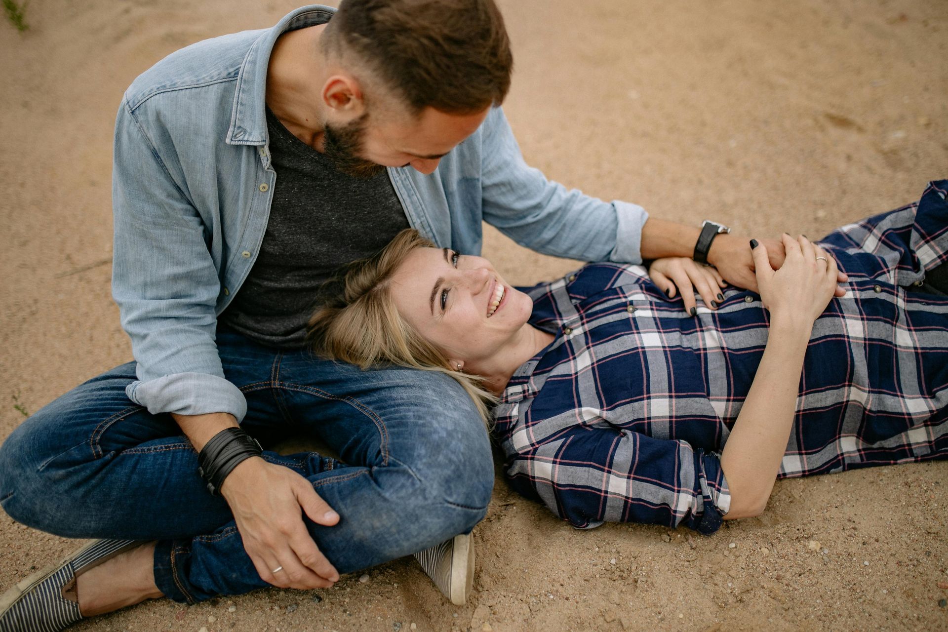 A man is sitting on the ground next to a woman laying on the ground.