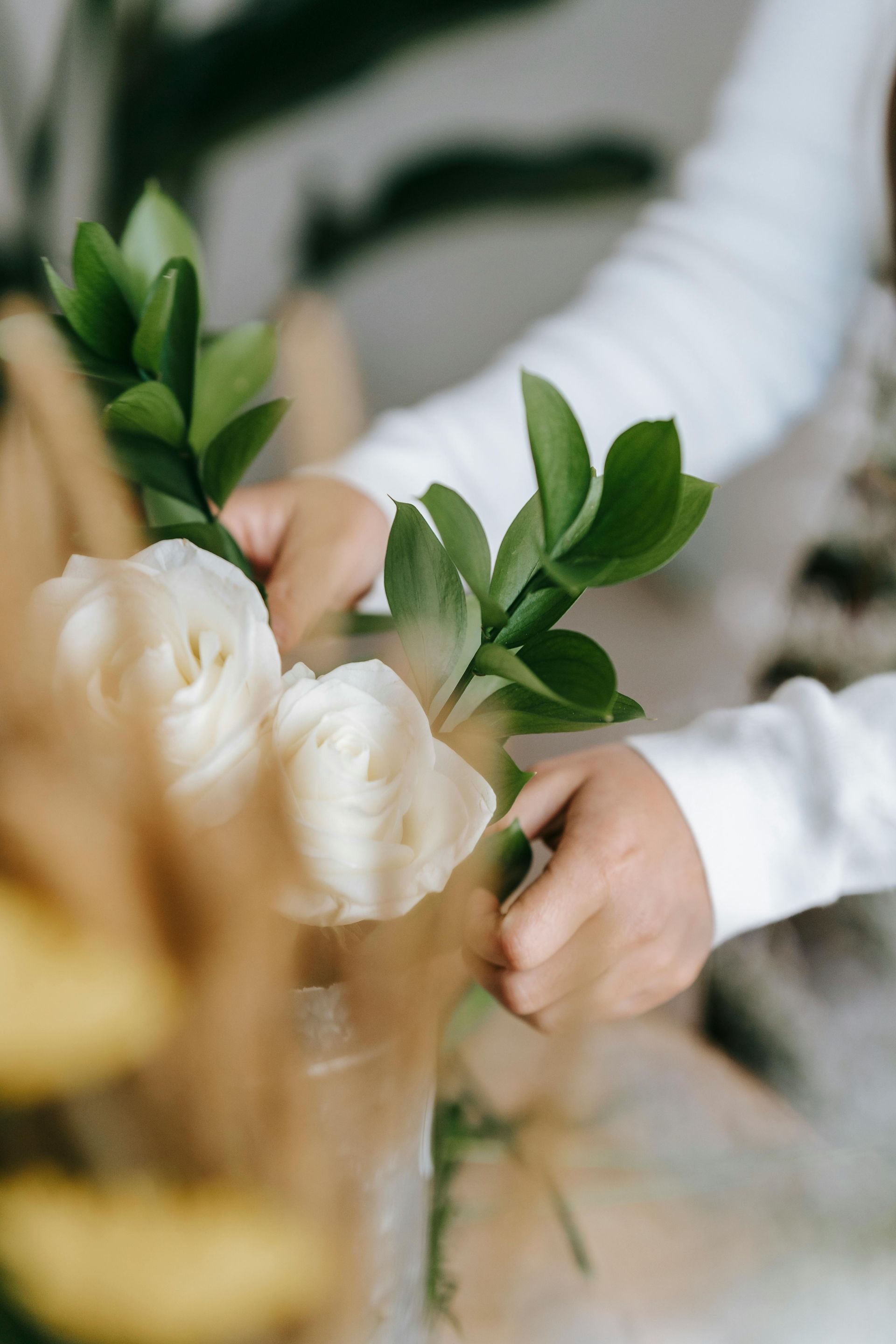 A person is arranging flowers in a vase on a table.