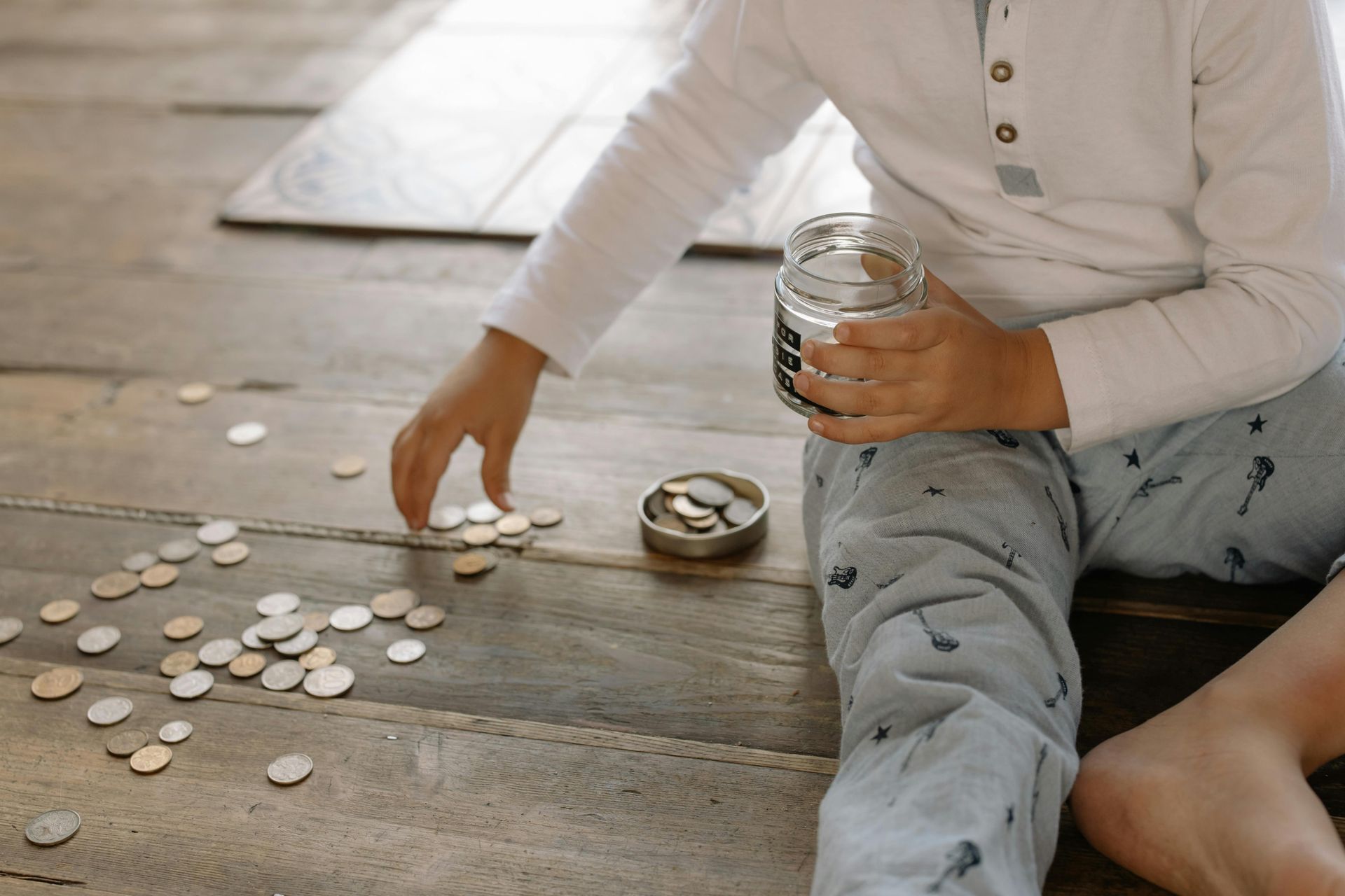 A young boy is sitting on the floor playing with coins.