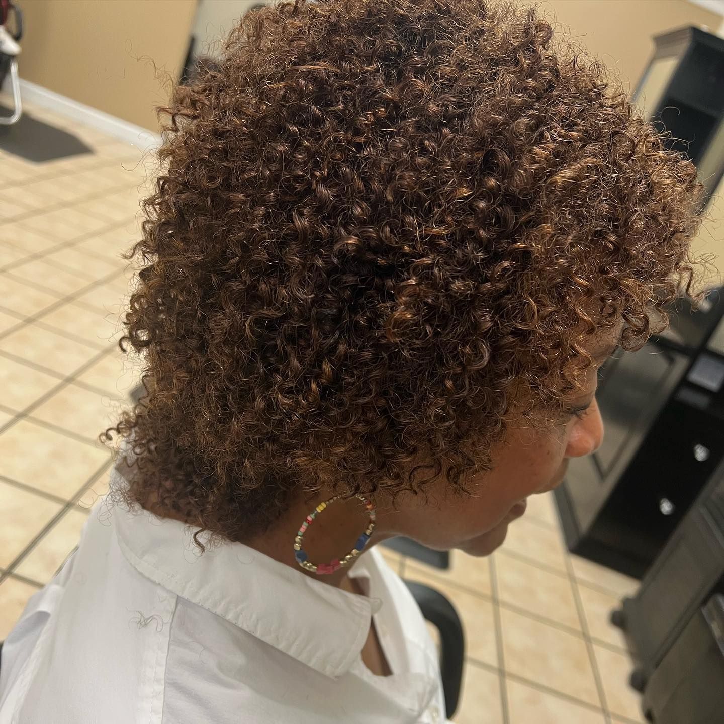 A woman with curly hair is wearing hoop earrings