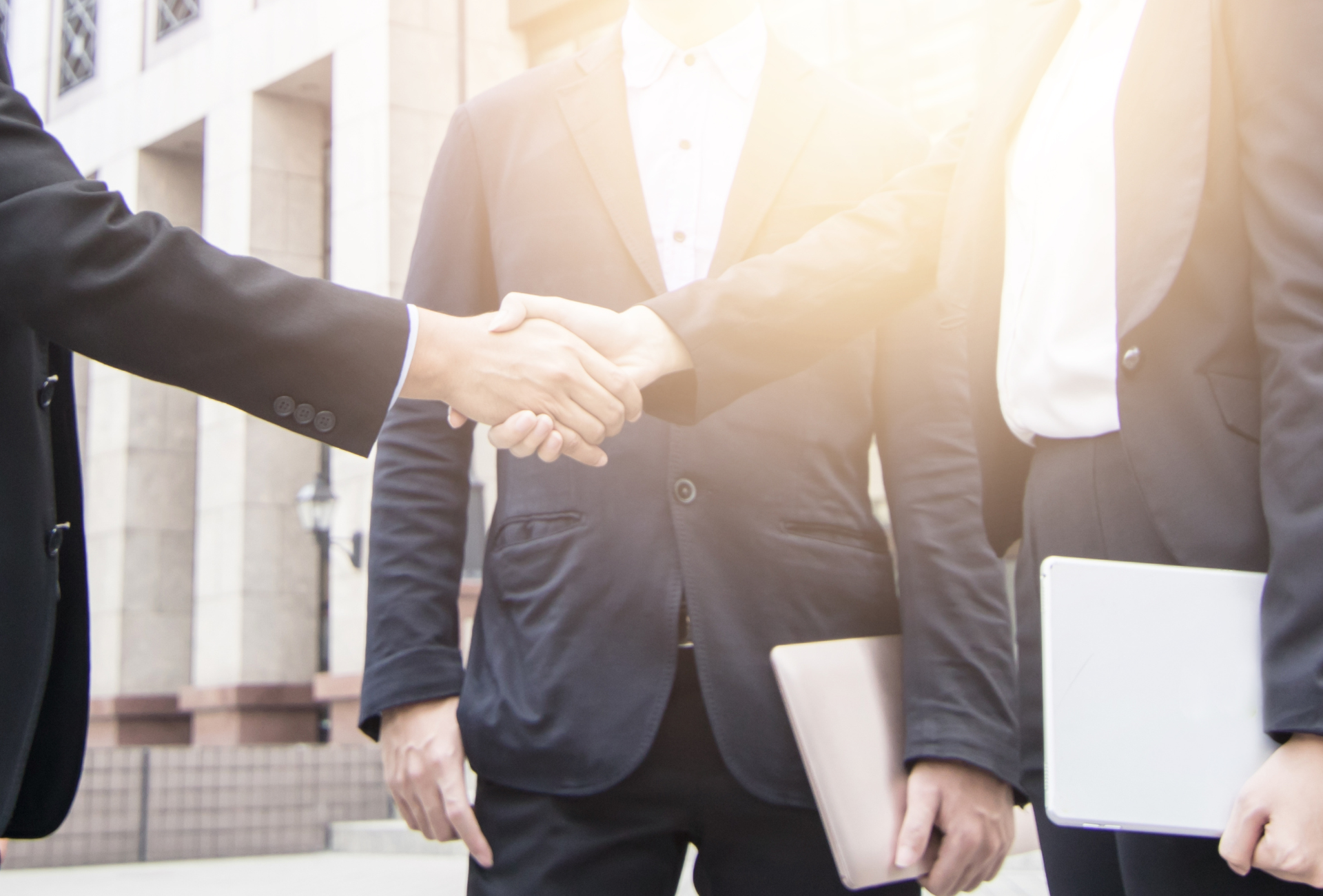 A group of business people shaking hands in front of a building.