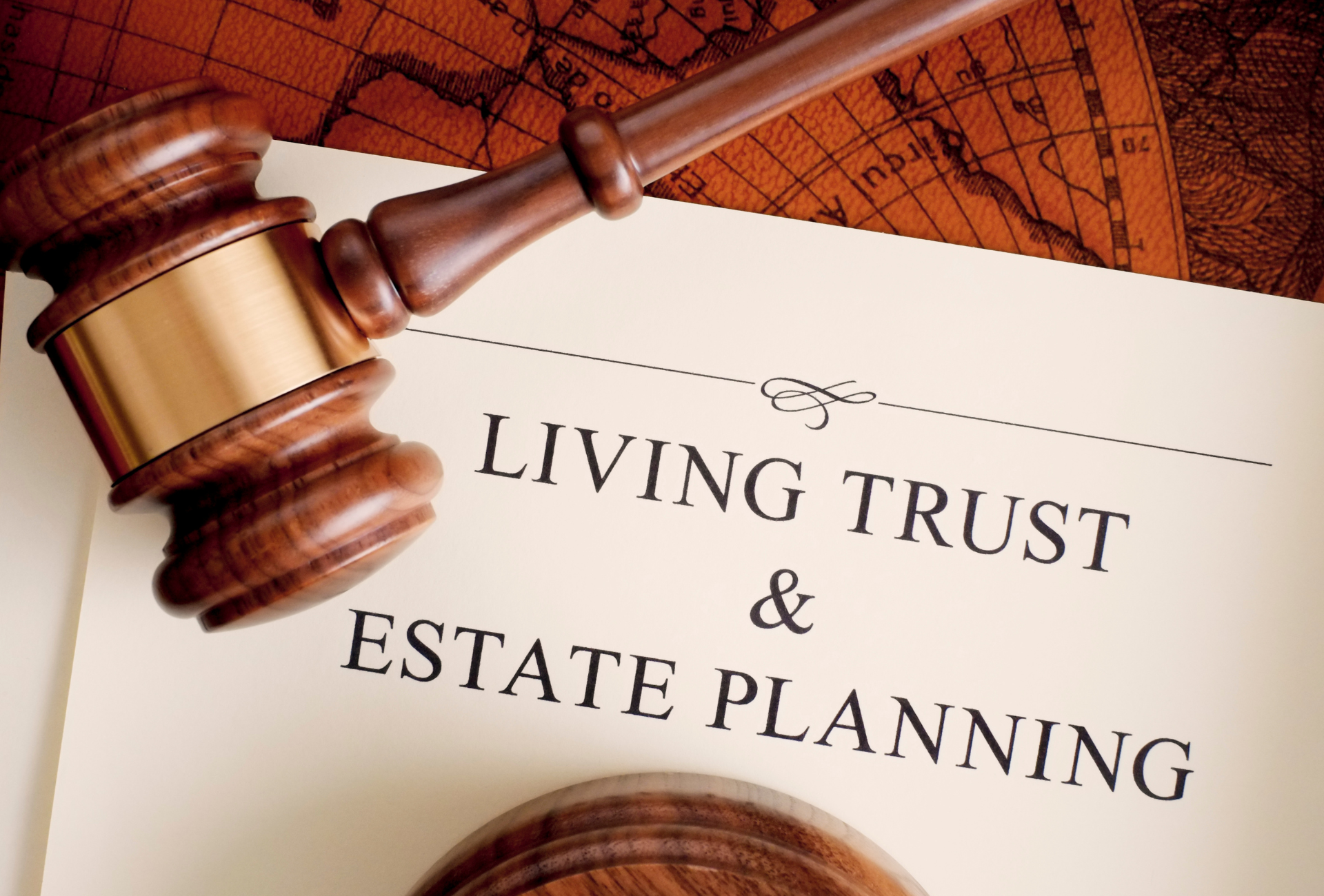 A wooden gavel sits on top of a book titled living trust and estate planning