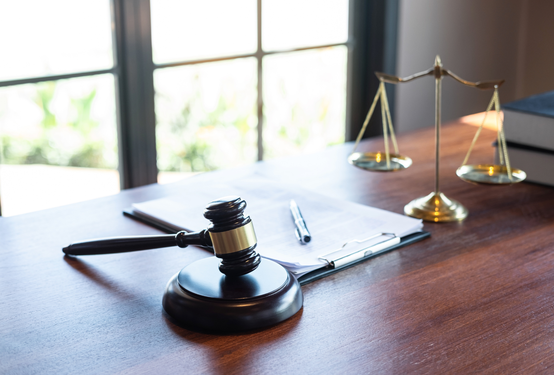 A judge 's gavel and scales of justice are on a wooden table.