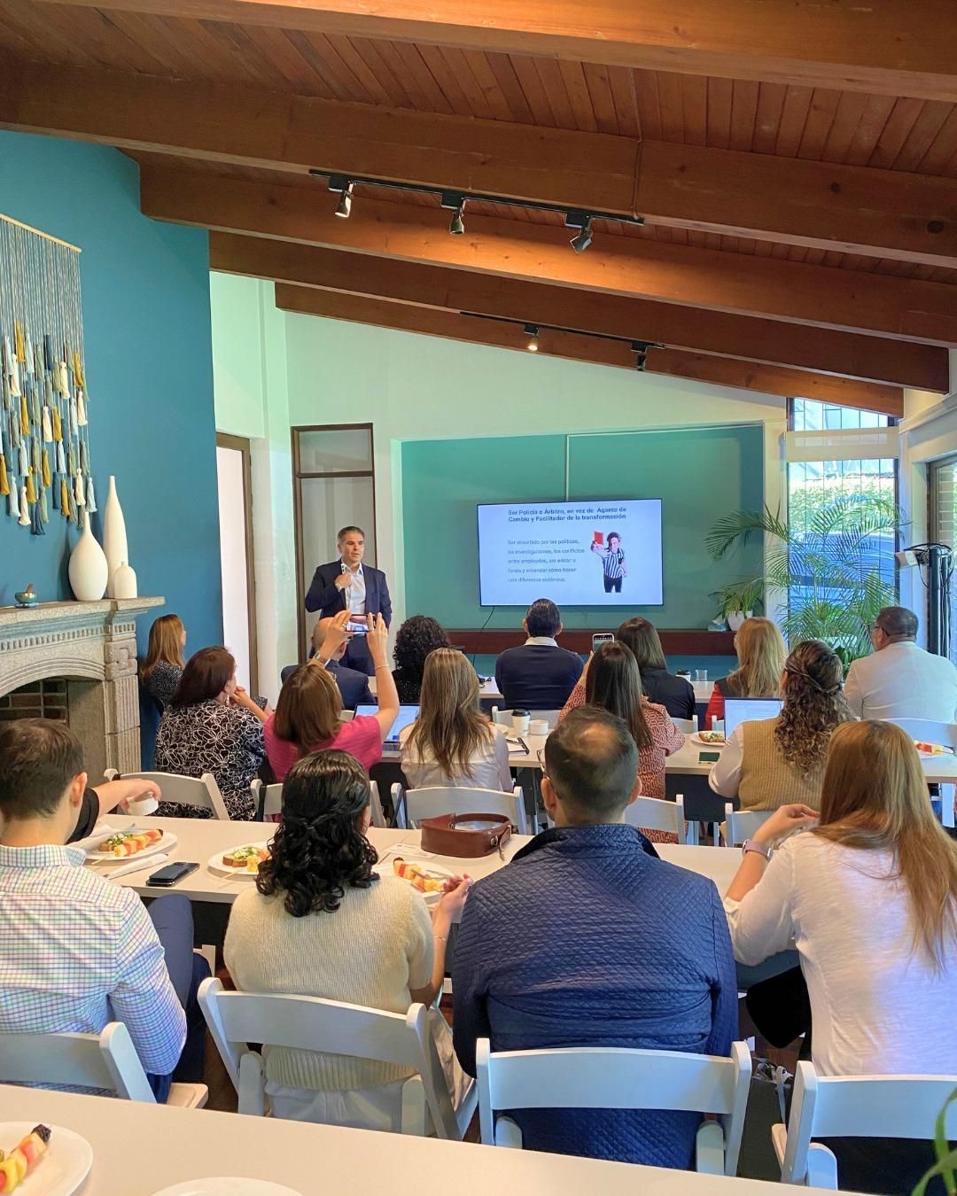 Three office workers collaborating at a whiteboard; woman in yellow top writes, others smile.