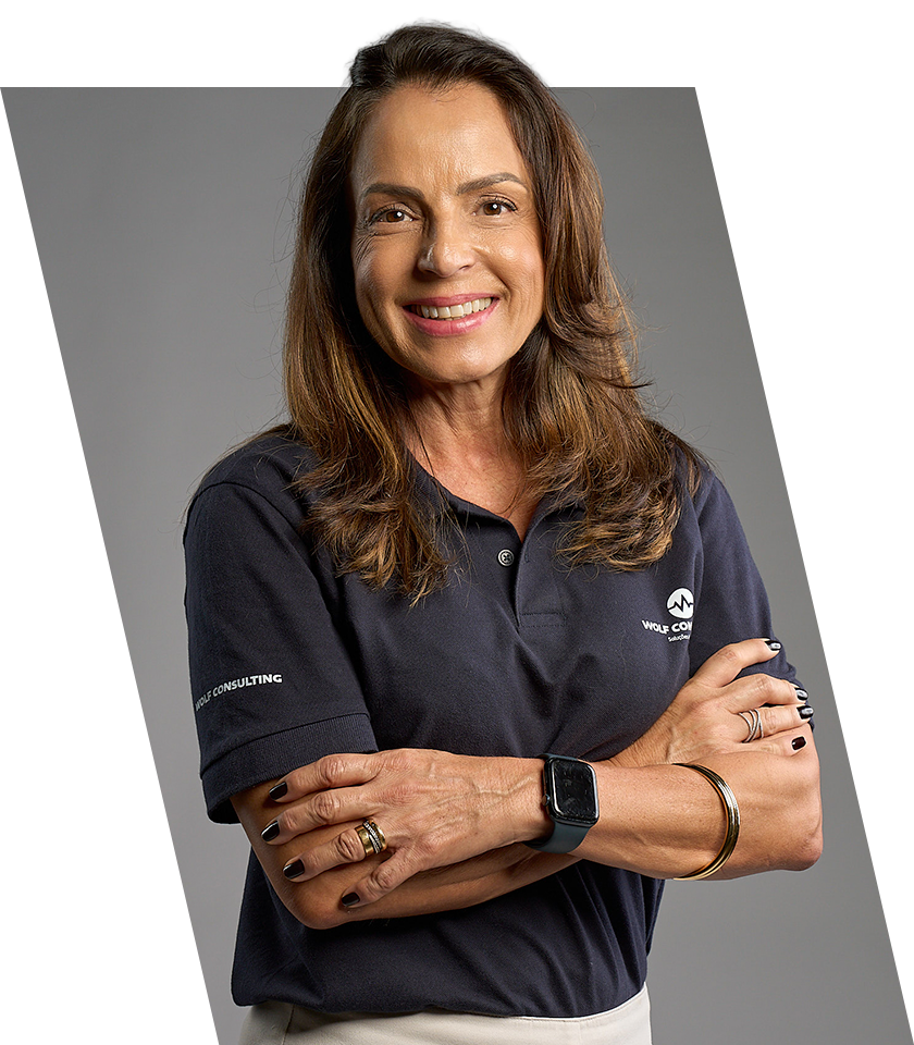 Mulher de blazer verde sorrindo, segurando um tablet, em ambiente interno.