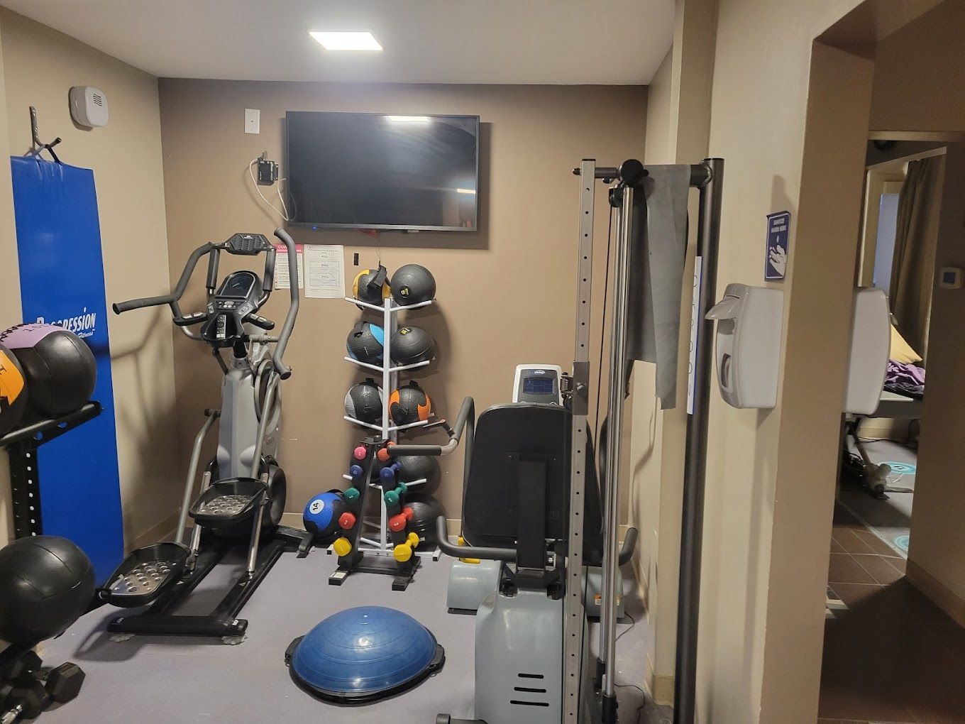A gym with a tv on the wall and a bunch of exercise equipment