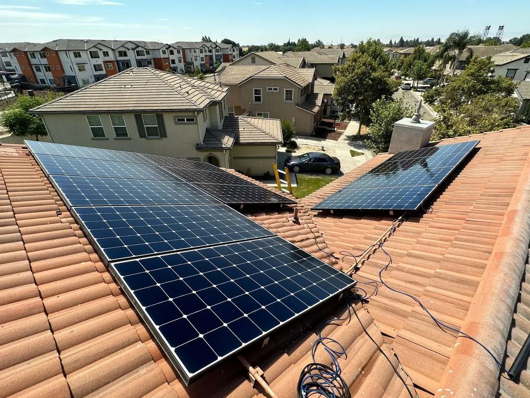 Two solar panels are sitting on top of a tiled roof.
