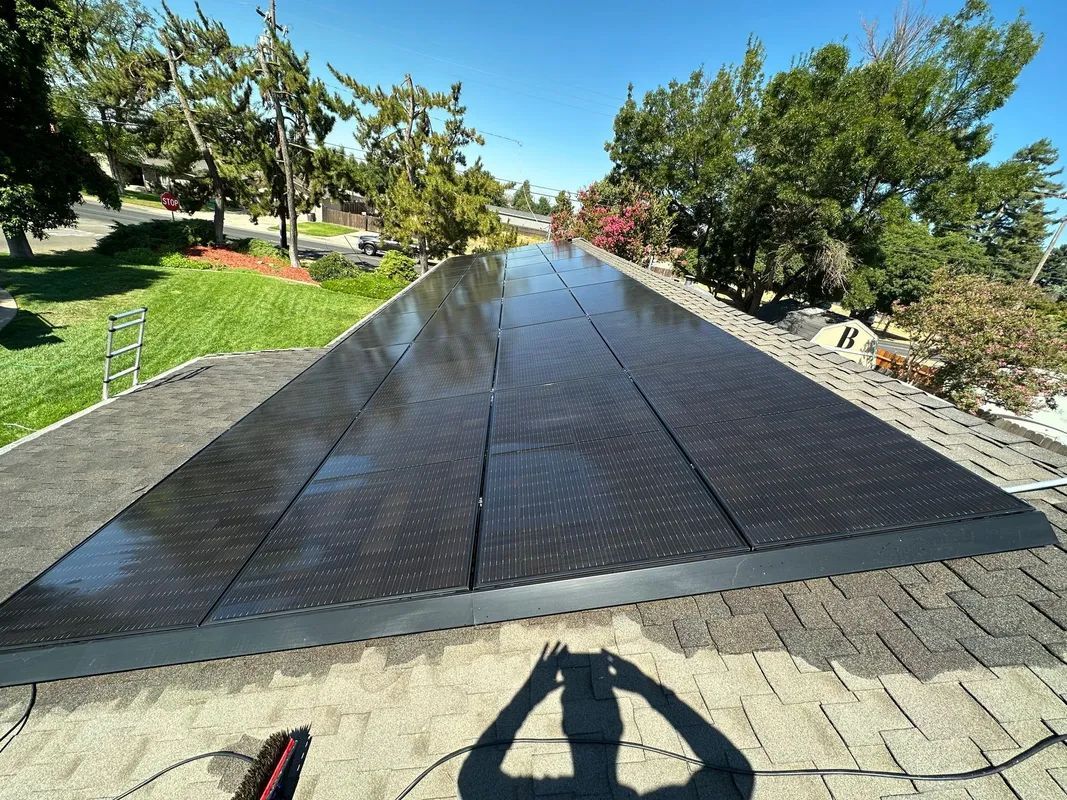 A person is taking a picture of a roof with solar panels on it.