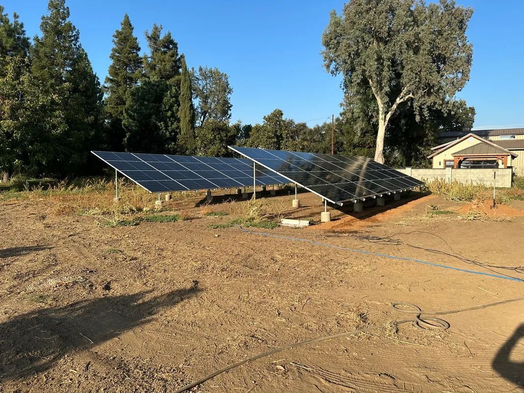 A group of solar panels are sitting on top of a dirt field.