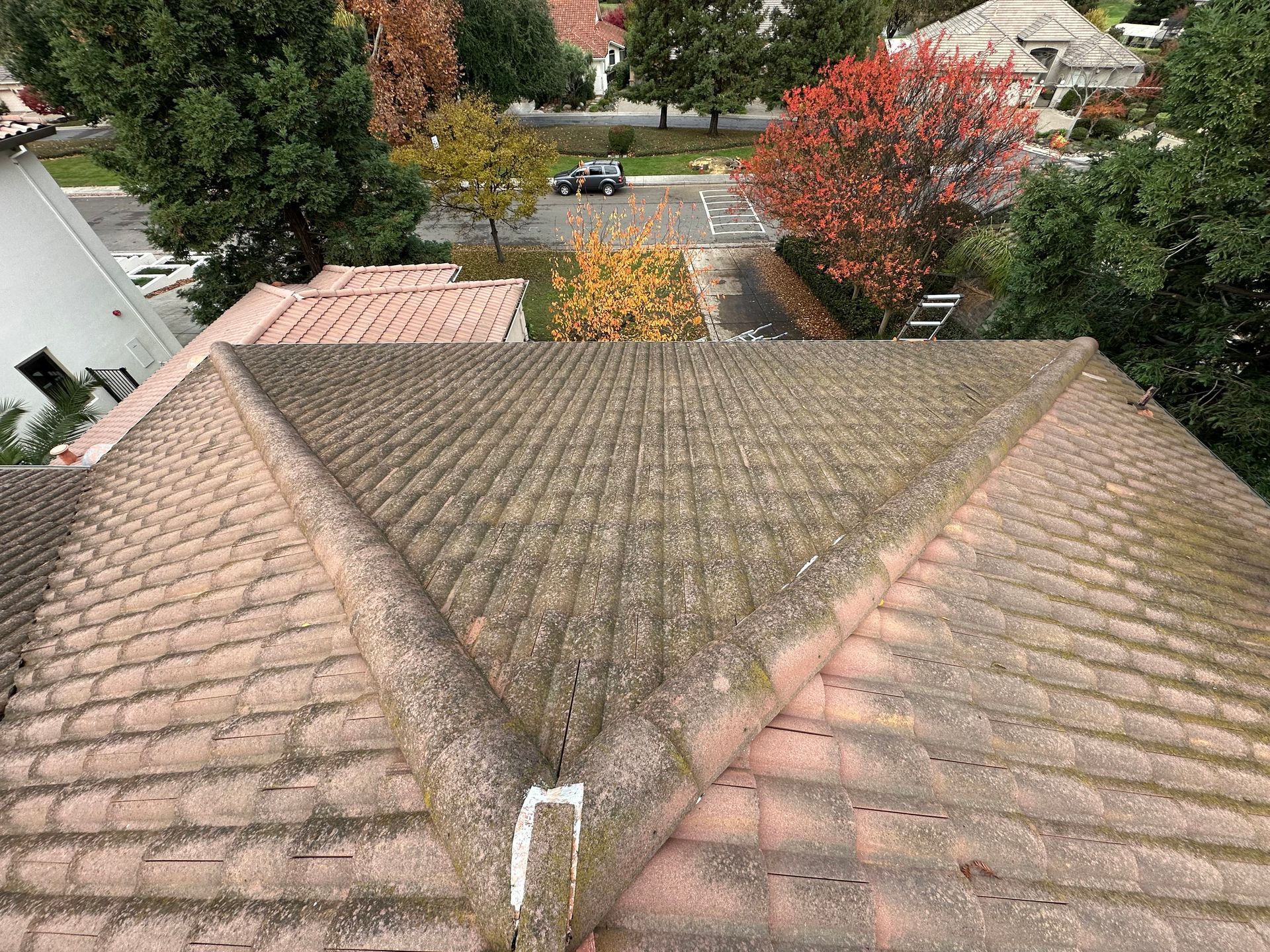 An aerial view of a roof of a house with trees in the background.