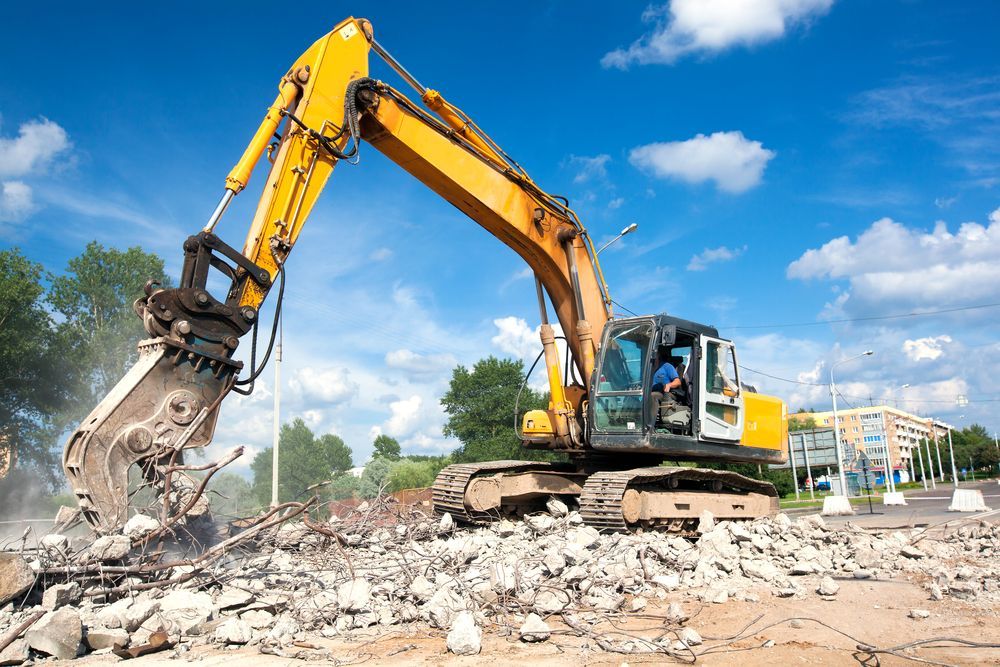 A Yellow Excavator Is Demolishing A Building On A Construction Site — ACC Excavations & Demolition Pty Ltd In Wollongong, NSW