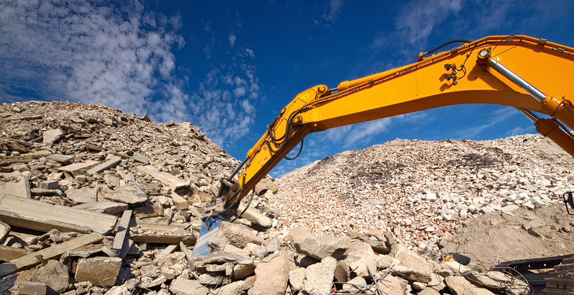As excavator is digging into a pile of debris.