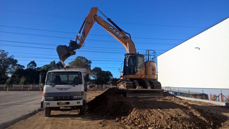 A Case Excavator Is Loading Dirt Into A Truck — ACC Excavations & Demolition Pty Ltd In Oak Floats, NSW