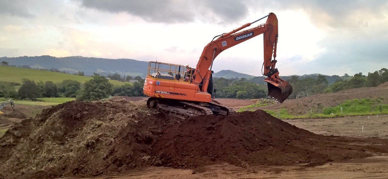 An Excavator Is Digging In A Pile Of Dirt In A Field — ACC Excavations & Demolition Pty Ltd In Oak Floats, NSW