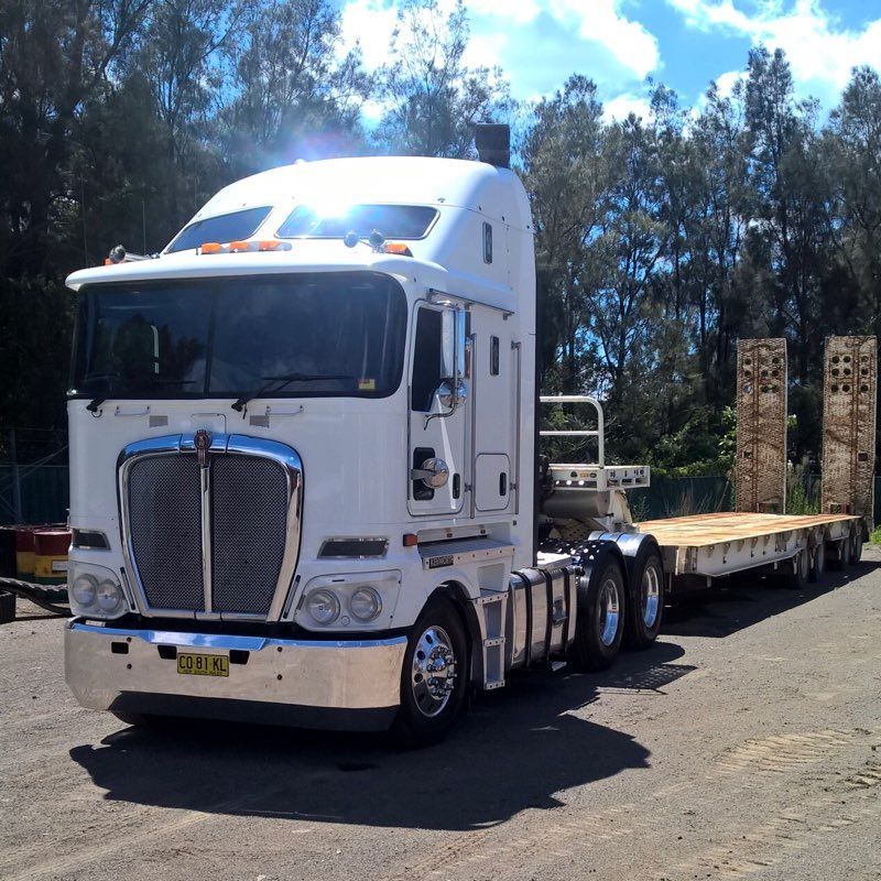 A Kenworth Semi Truck With A Flatbed Trailer Attached — ACC Excavations & Demolition Pty Ltd In Nowra, NSW