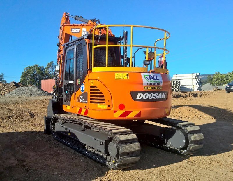 An Orange Doosan Excavator Is Parked In A Dirt Field — ACC Excavations & Demolition Pty Ltd In Ulladulla, NSW