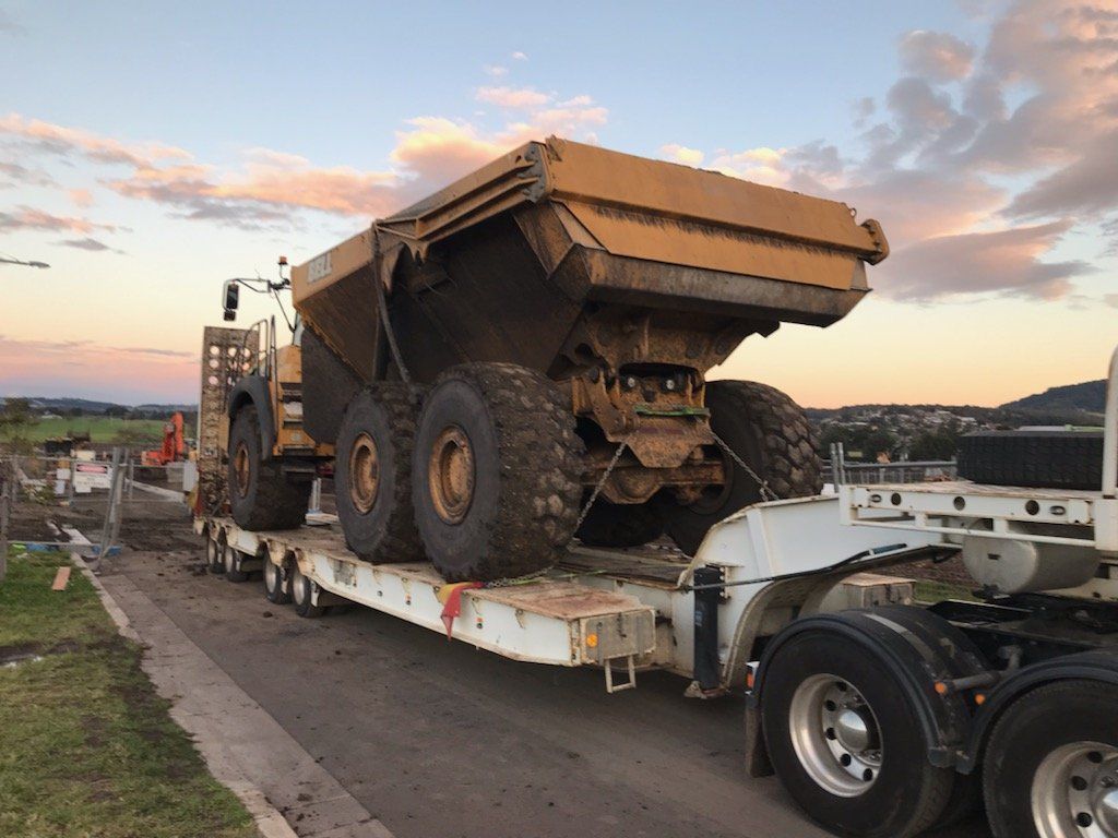 A Large Dump Truck Is Being Transported On A Trailer — ACC Excavations & Demolition Pty Ltd In Oak Floats, NSW