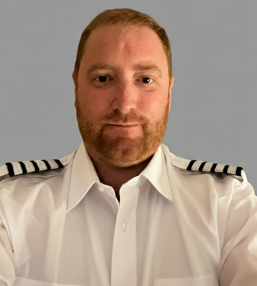 Man in white uniform with captain's stripes, medium shot, looking at the camera.