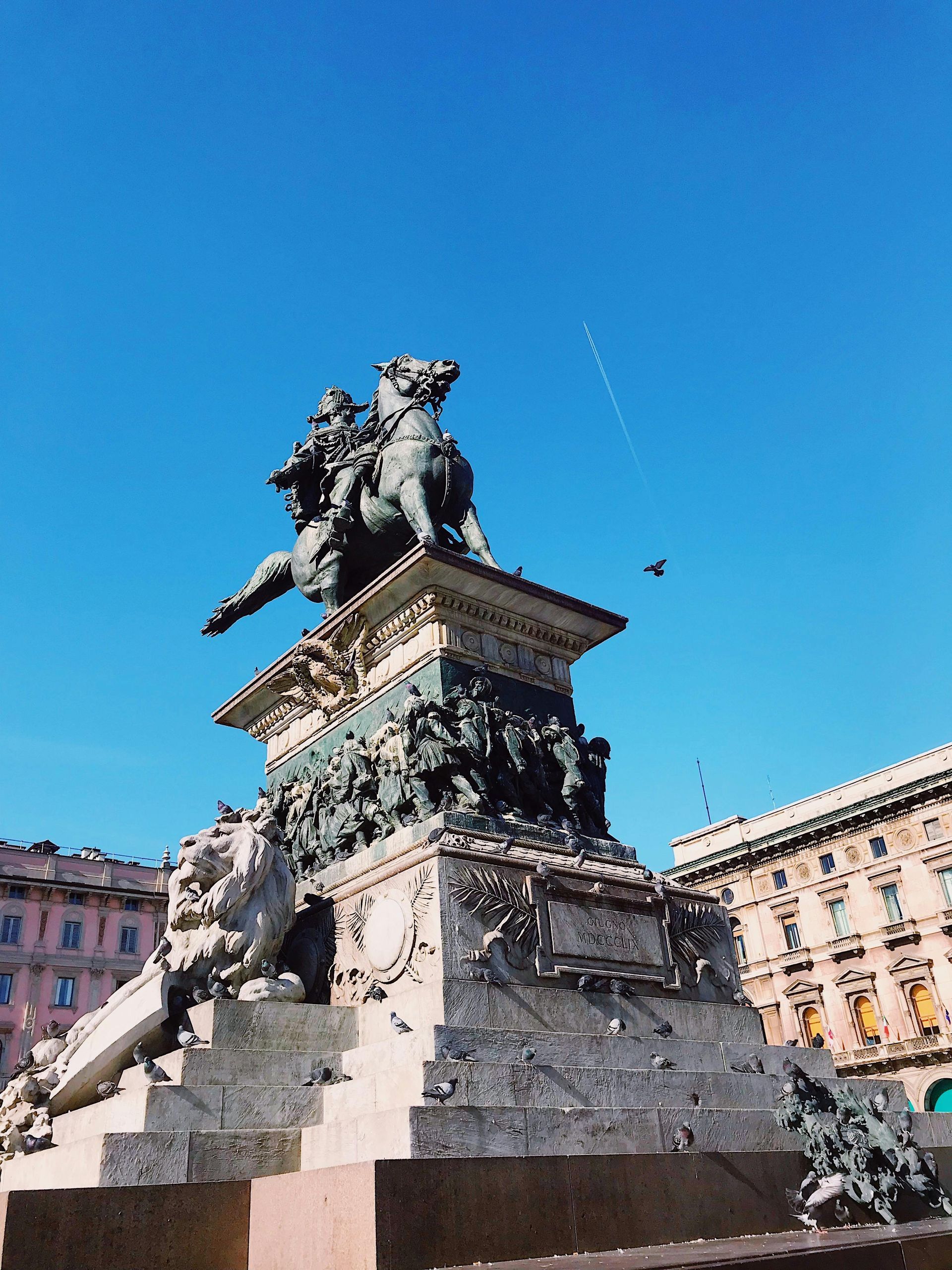 Equestrian statue of Victor Emmanuel II in Milan, Italy against a blue sky.