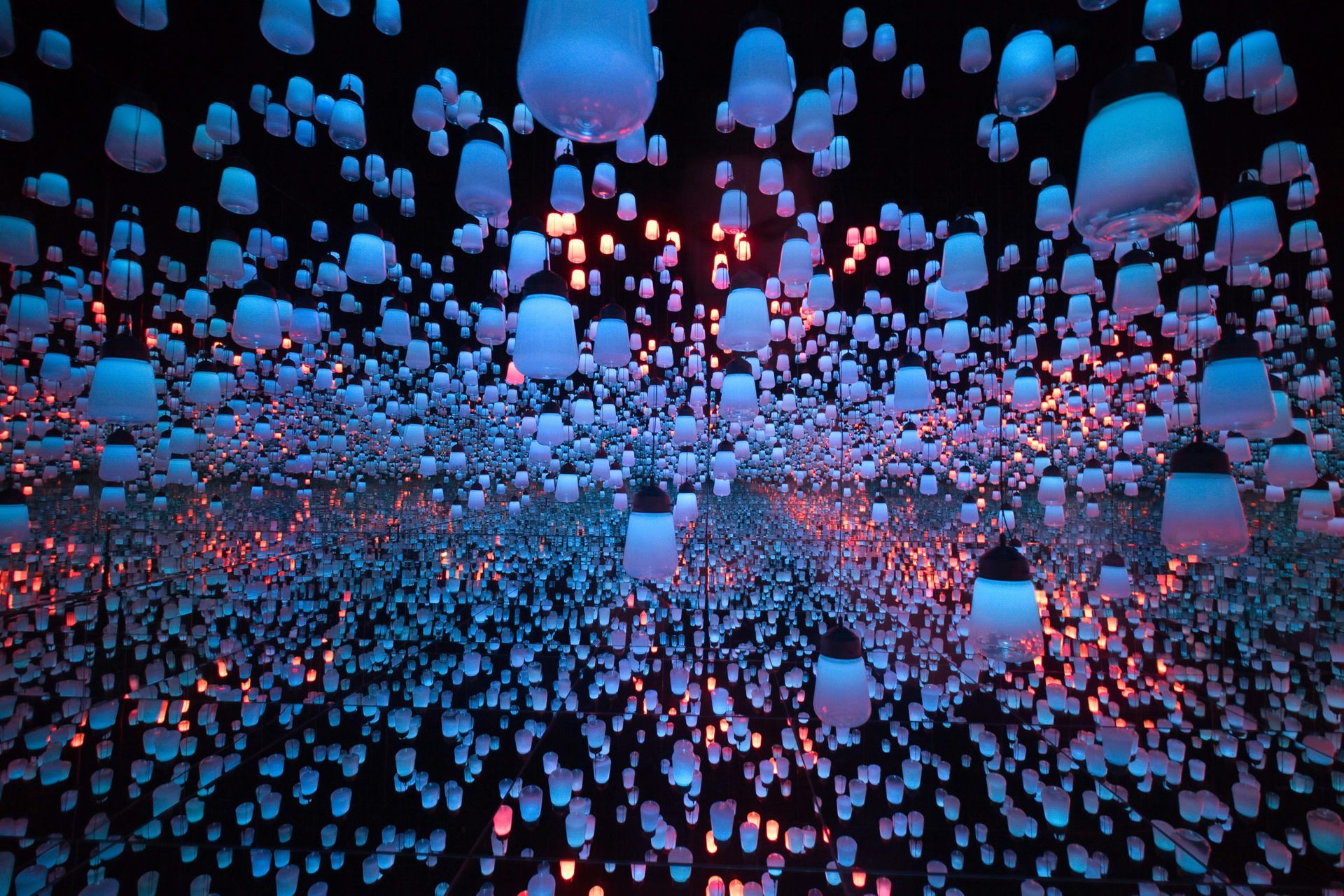 Floating illuminated lanterns in a dark room, with blue and orange hues creating an immersive, endless space.