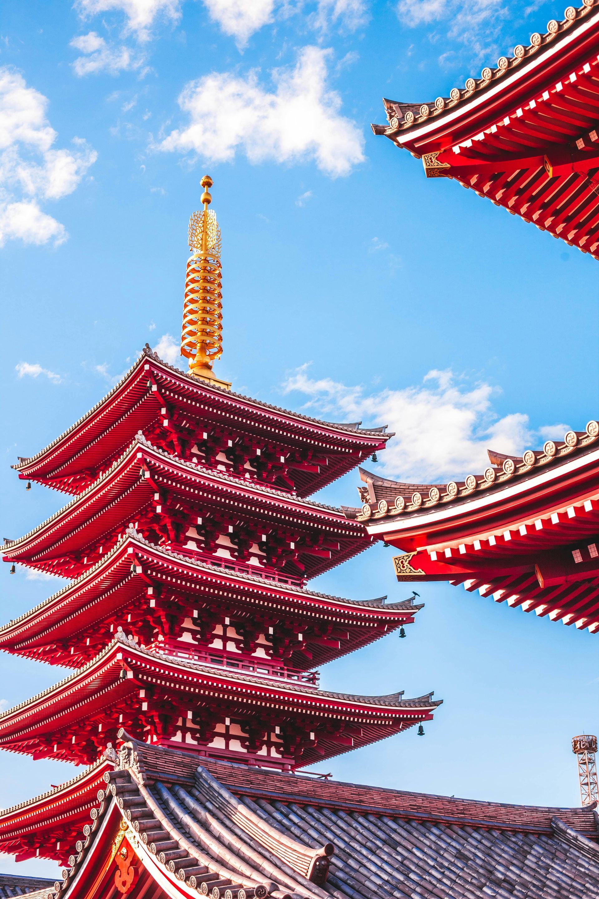 Red and gold pagoda against a bright blue sky in Japan.