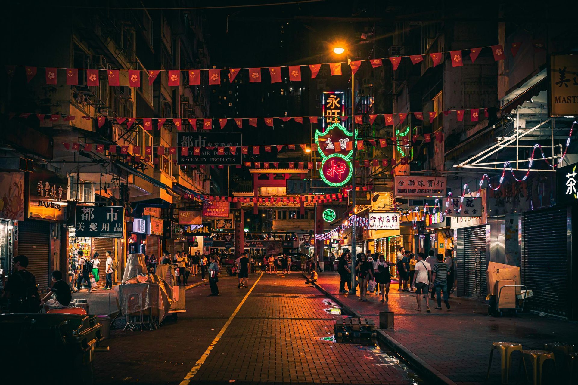 Night scene in Chinatown, Hong Kong. Busy street with lights, people, and red banners.
