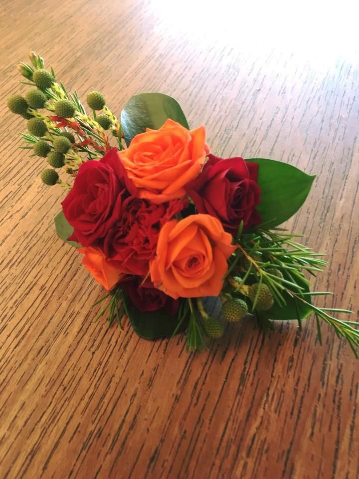 A Bouquet of Red and Orange Roses is Sitting on a Wooden Table — Flower Hunt in Robina, QLD