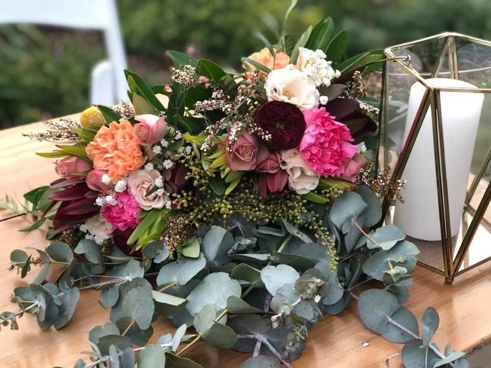 A Table With Flowers and a Candle on It — Flower Hunt in Robina, QLD