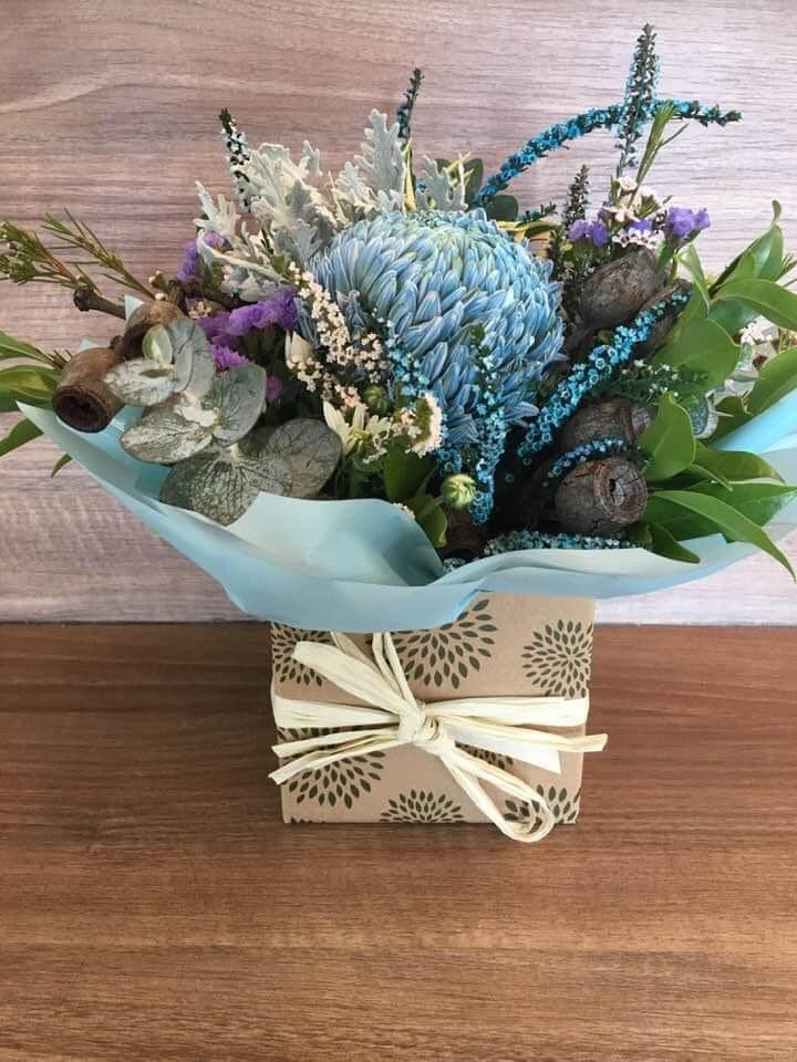 A Box Filled With Flowers is Sitting on a Wooden Table — Flower Hunt in Robina, QLD