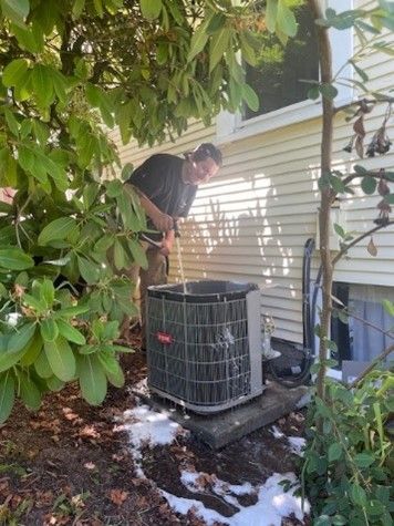 A man wearing a green vest is engaged in air conditioner repair, demonstrating safety and expertise.