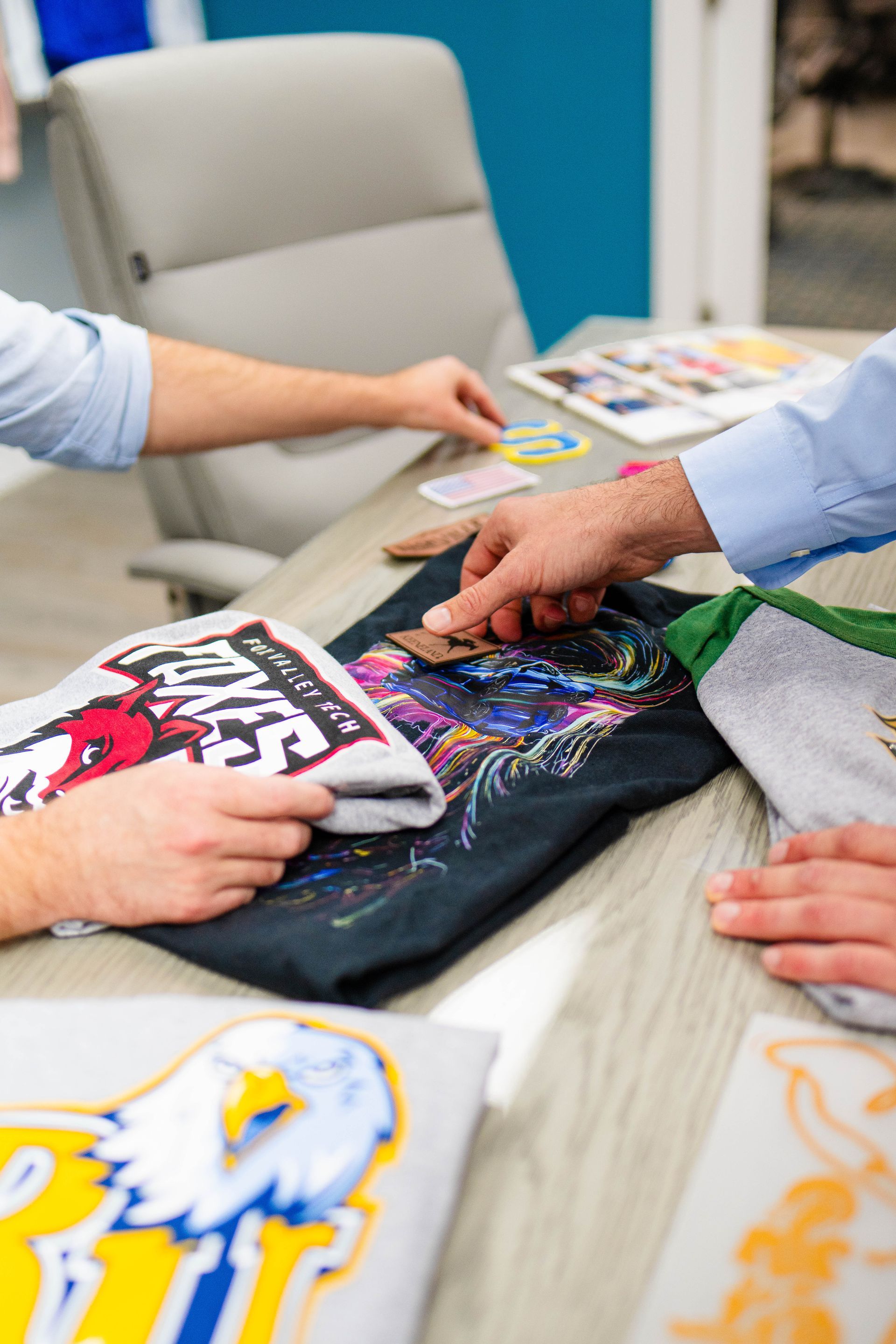 A group of people are sitting at a table looking at a t-shirt.
