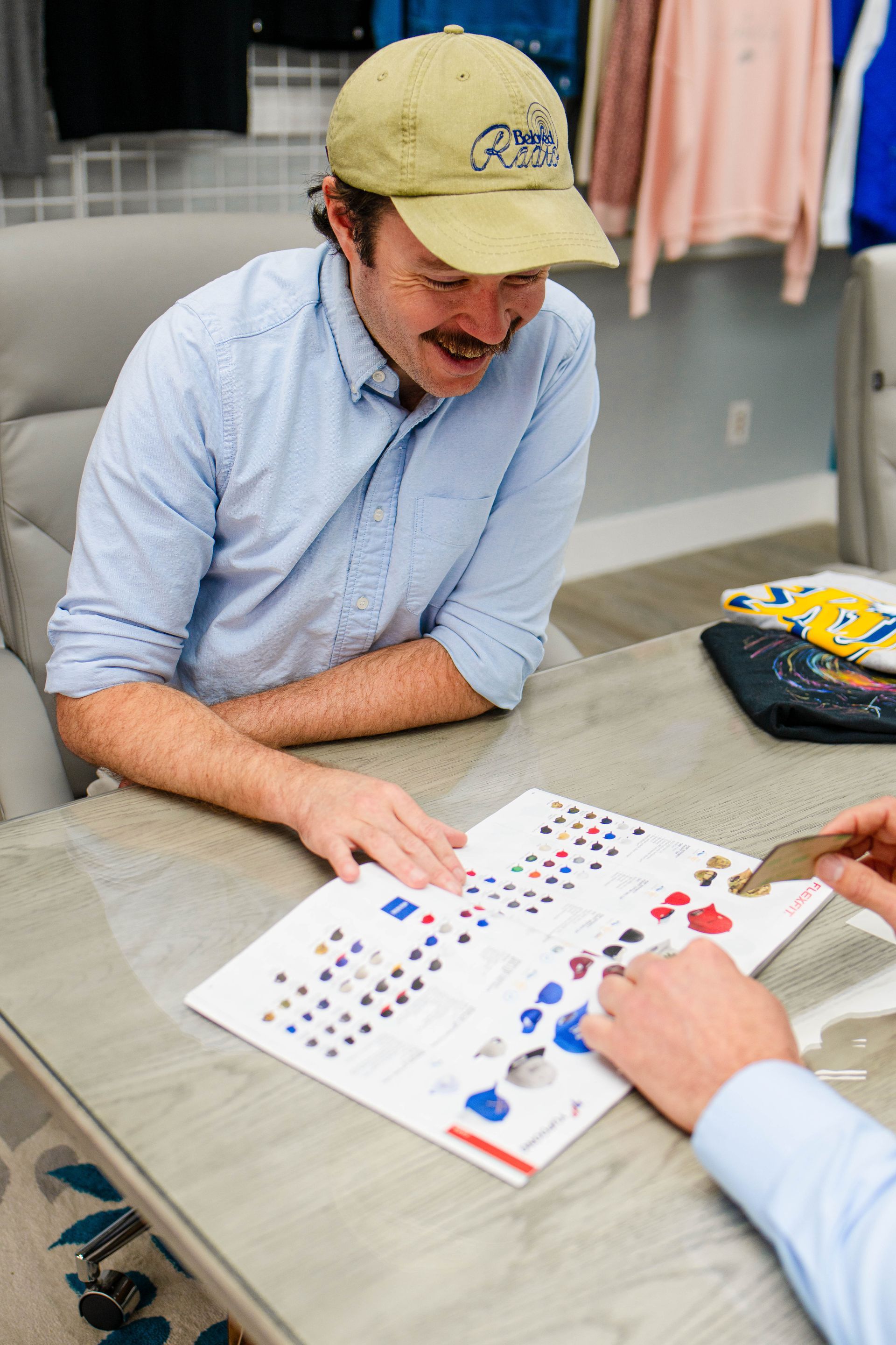 A man in a hat is sitting at a table looking at a piece of paper.