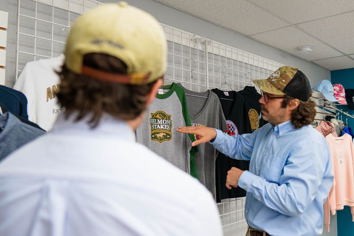 A man is pointing at a shirt in a store while another man looks on.